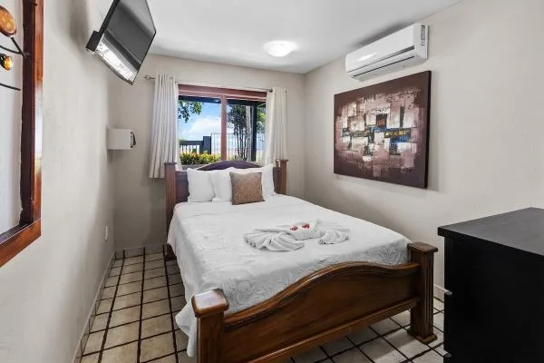 Un dormitorio con una cama de madera, ropa de cama blanca y una ventana.
