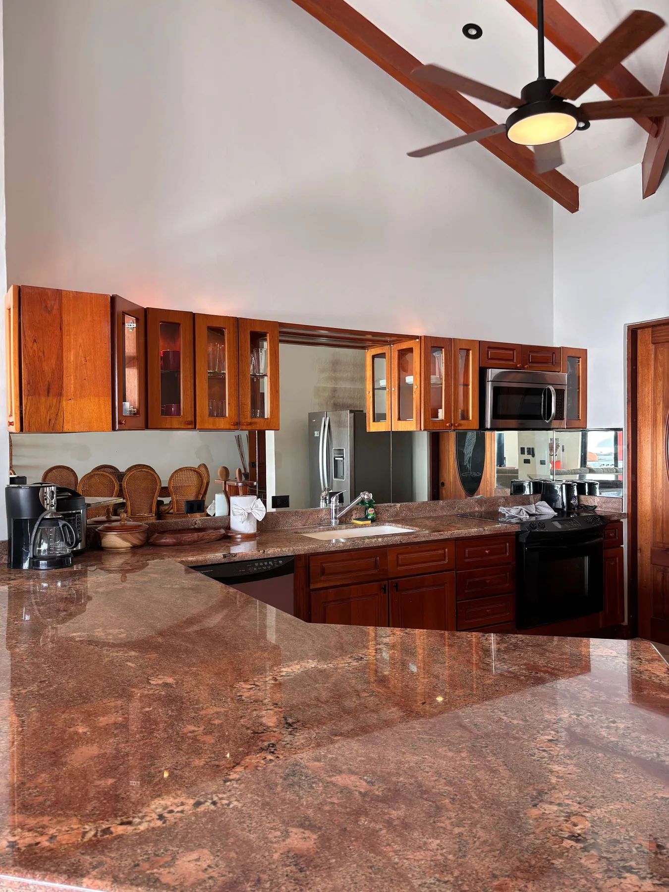 A spacious kitchen with wooden cabinets and a large polished stone countertop.