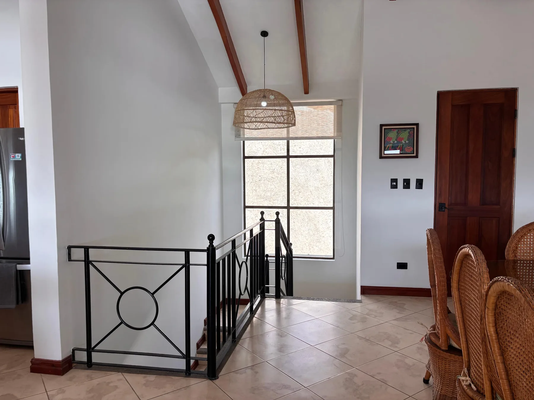 A dining area with a window, pendant light, and staircase railing.