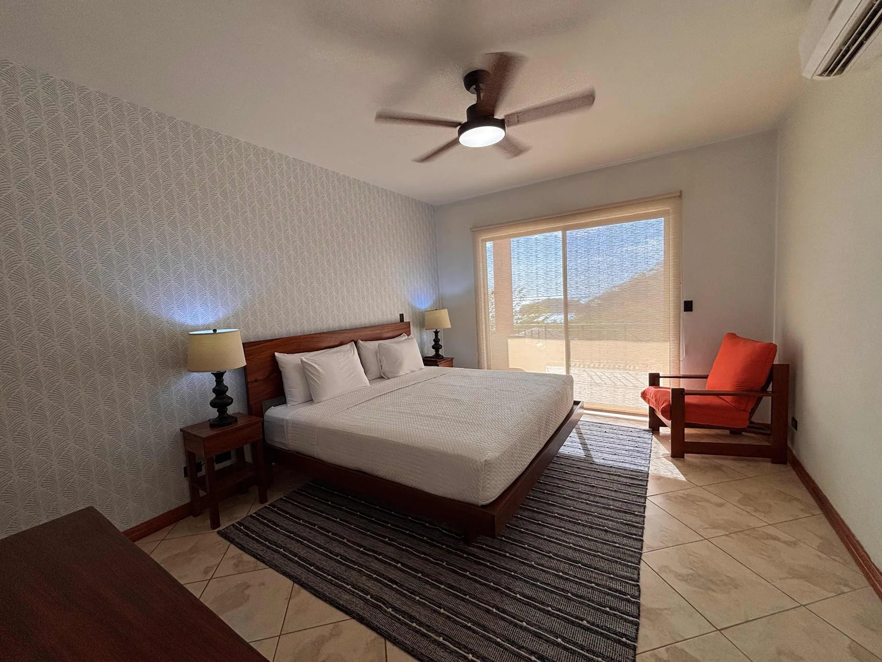 A bedroom with a bed, bedside tables, and a bright window.