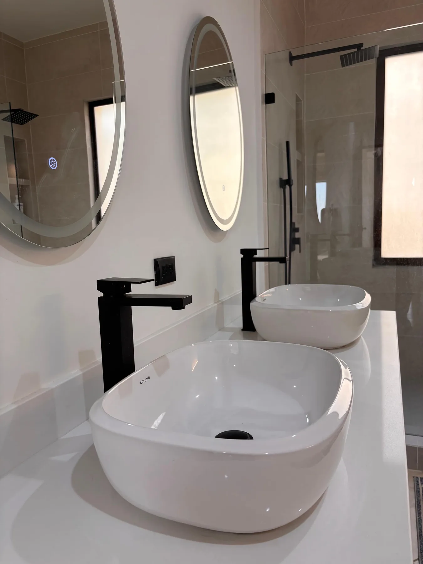 A modern bathroom with two white vessel sinks and mirrors.