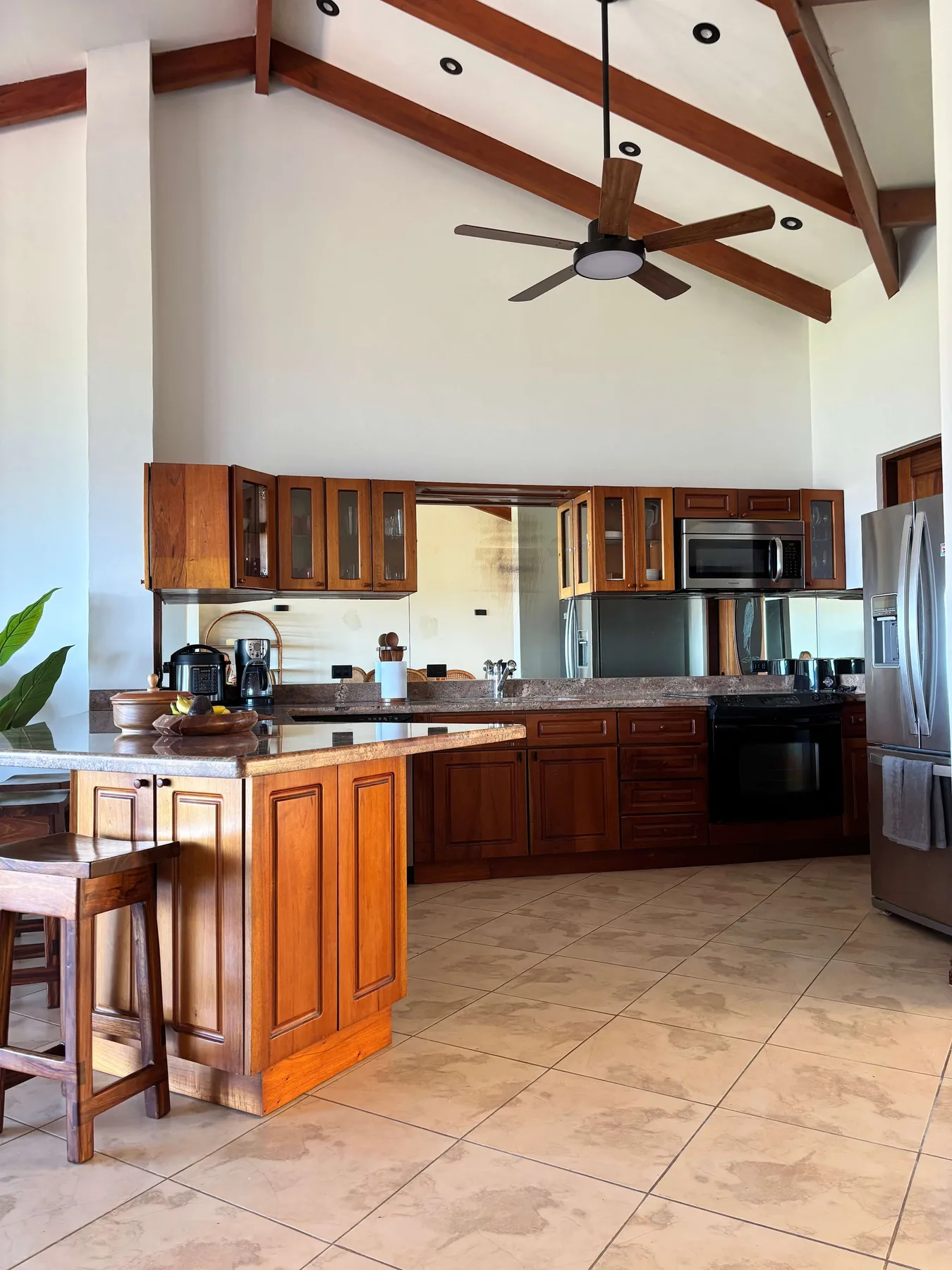 A spacious kitchen with wooden cabinets, a central island, and a ceiling fan.