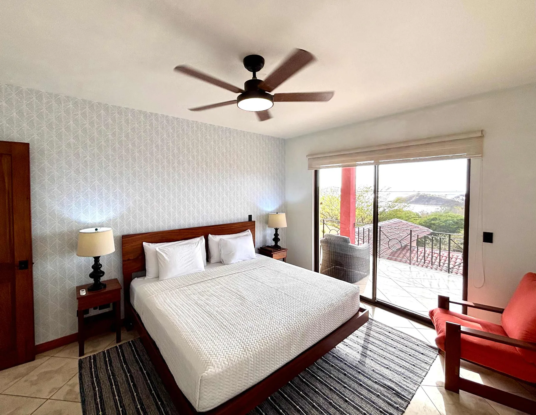 A bedroom with a bed, bedside lamps, and sliding glass doors opening onto a balcony.
