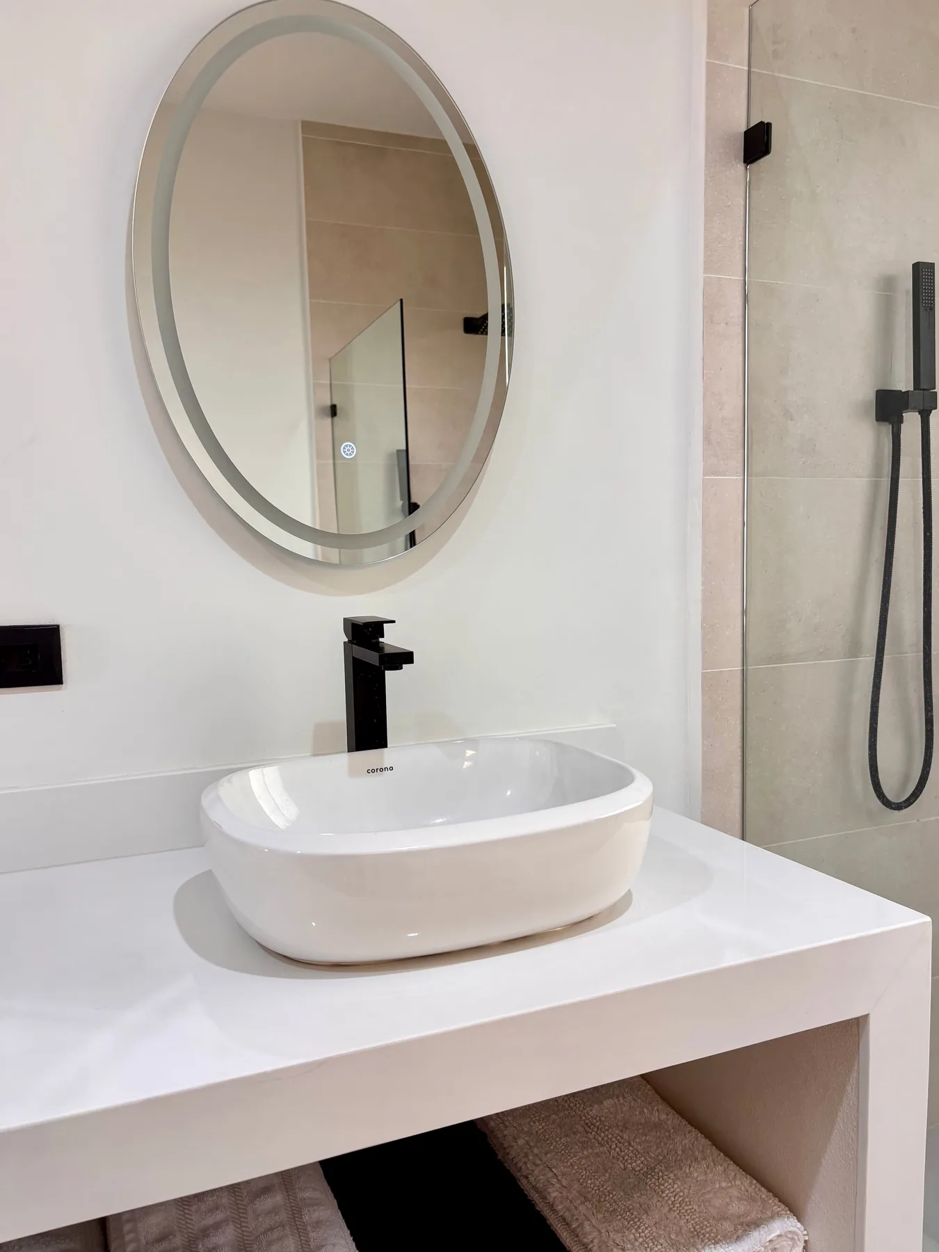 A bathroom vanity with a vessel sink, oval mirror, and shower.