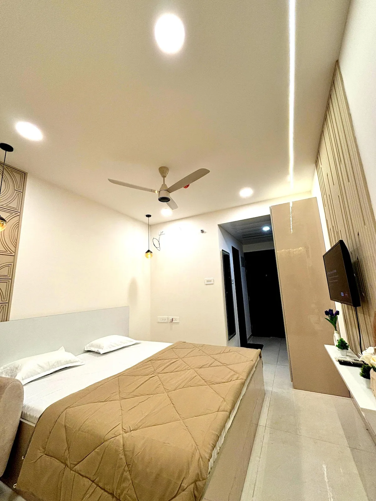 Un dormitorio con una cama, ventilador de techo y televisor.