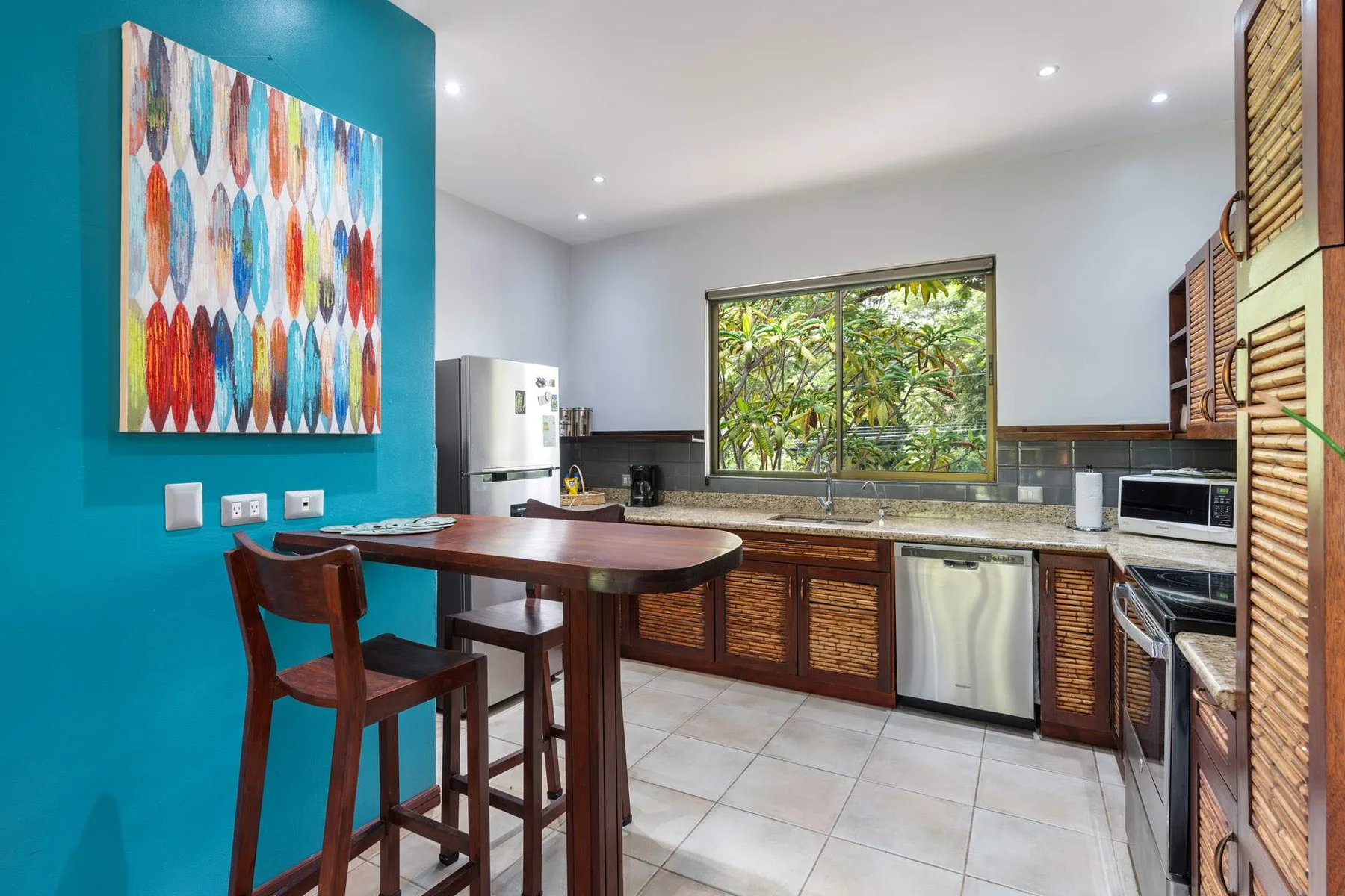 Una cocina luminosa con barra, electrodomésticos de acero inoxidable y una ventana amplia.
