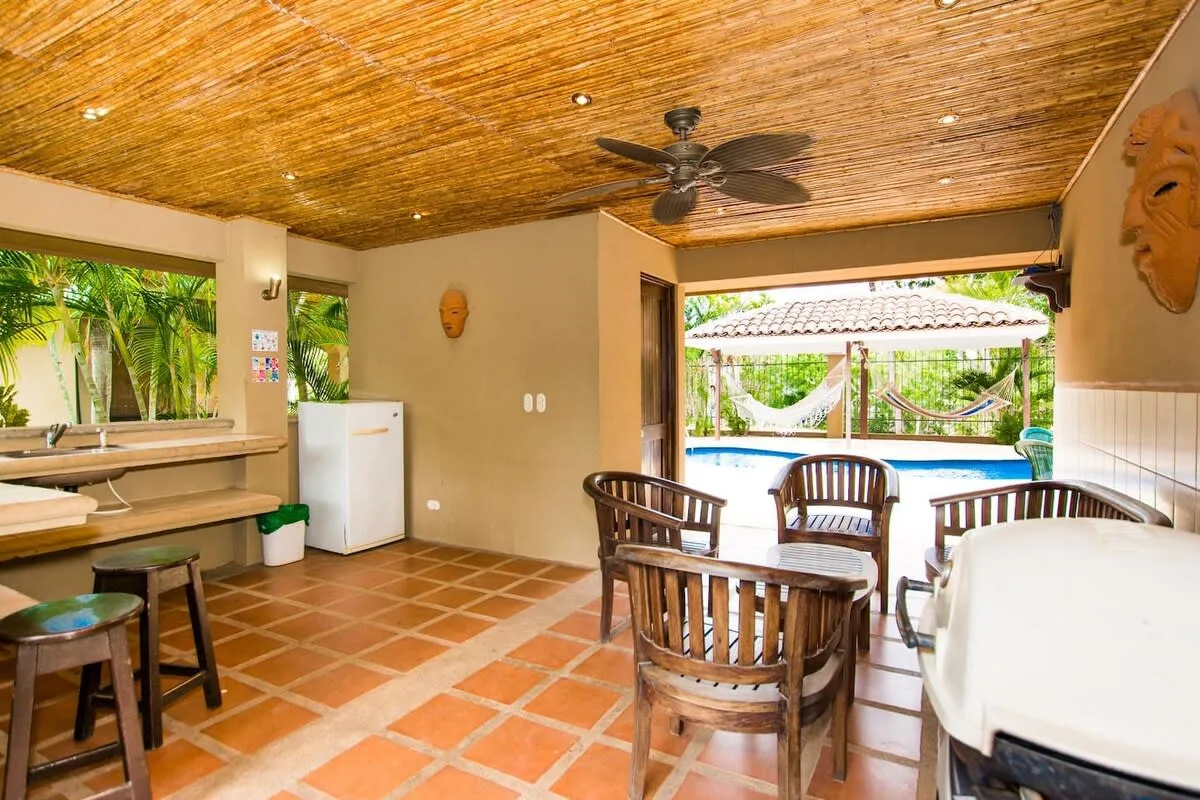 Zona común: Un comedor cubierto con asientos de madera da a un patio junto a la piscina.