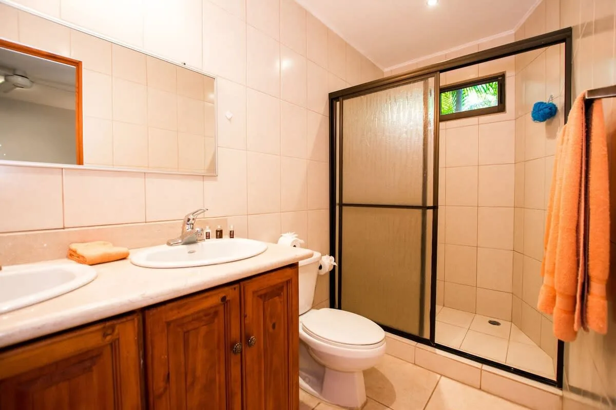 Un baño con azulejos, lavabo, inodoro y mampara de ducha.