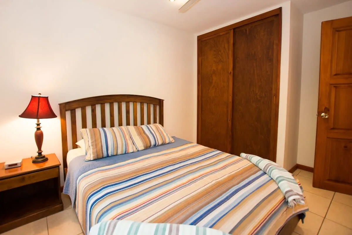 Un dormitorio con una cama de madera y ropa de cama a rayas junto a una mesita de noche.