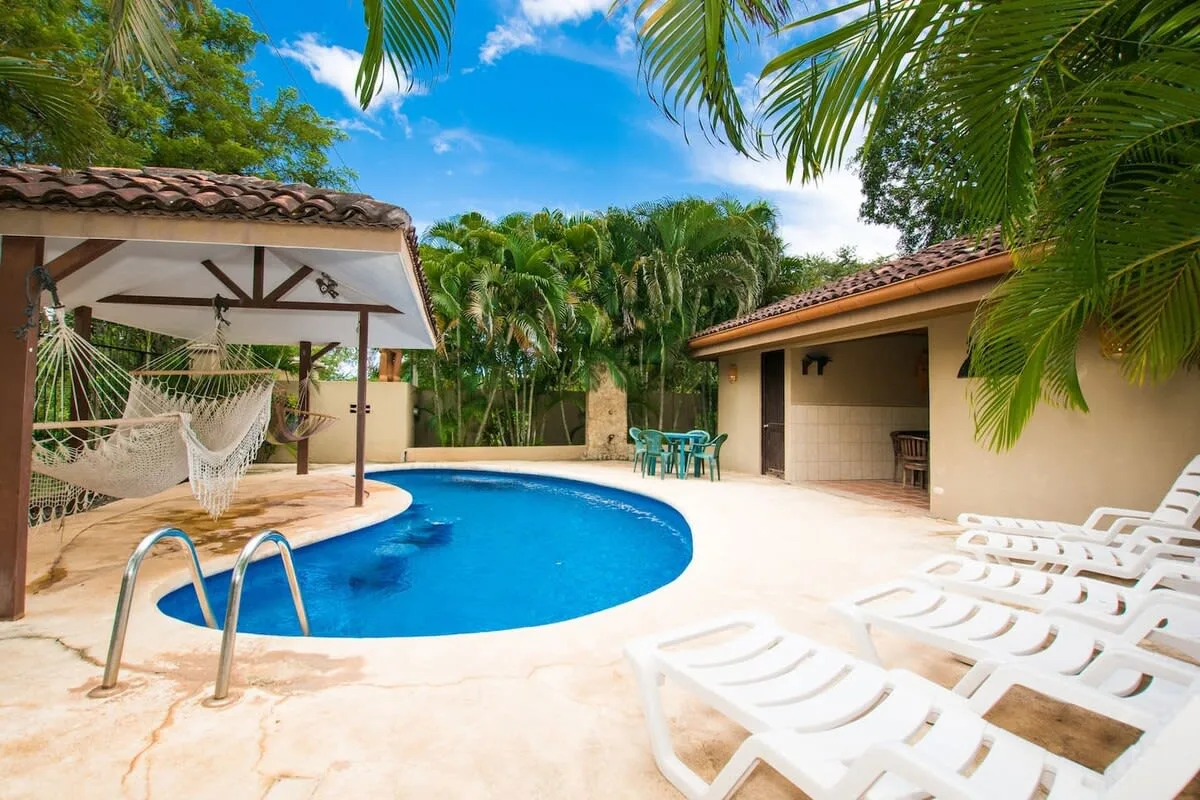 Shared amenity: A tropical pool area with lounge chairs and a shaded hammock seating area.
