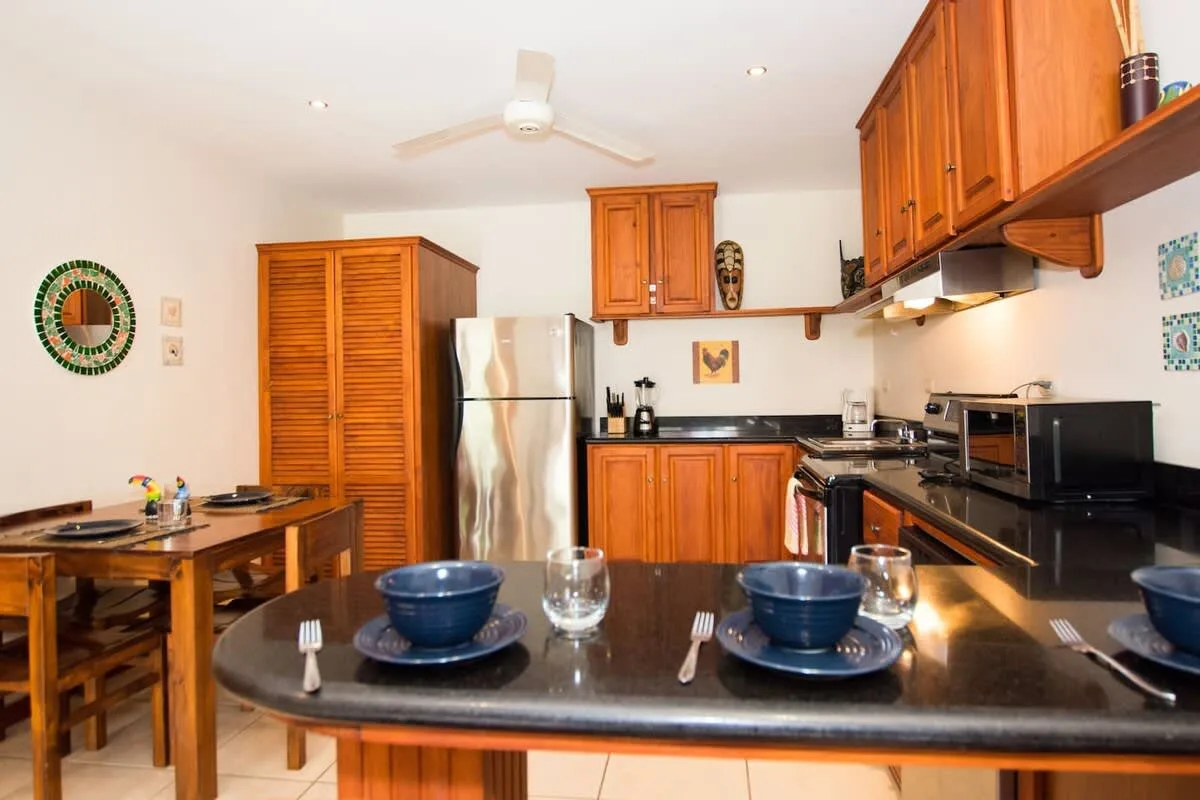 Una cocina y comedor con gabinetes de madera y una mesa puesta con platos.