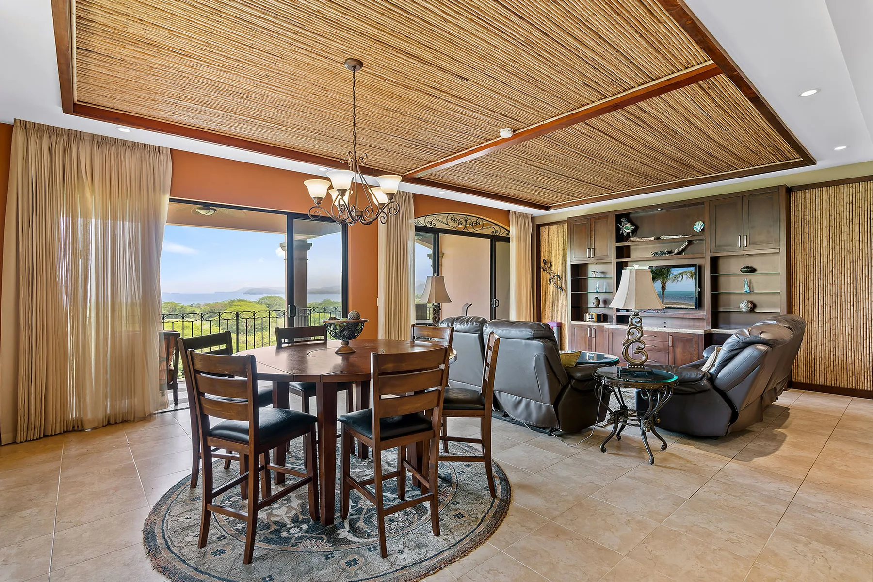 A living and dining area with a wooden table and seating beside large windows.