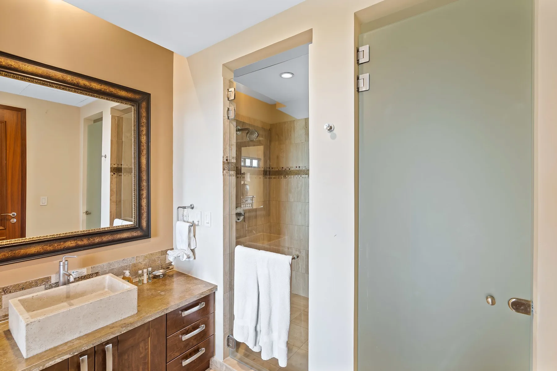 A bathroom with a vanity, large mirror, and shower.