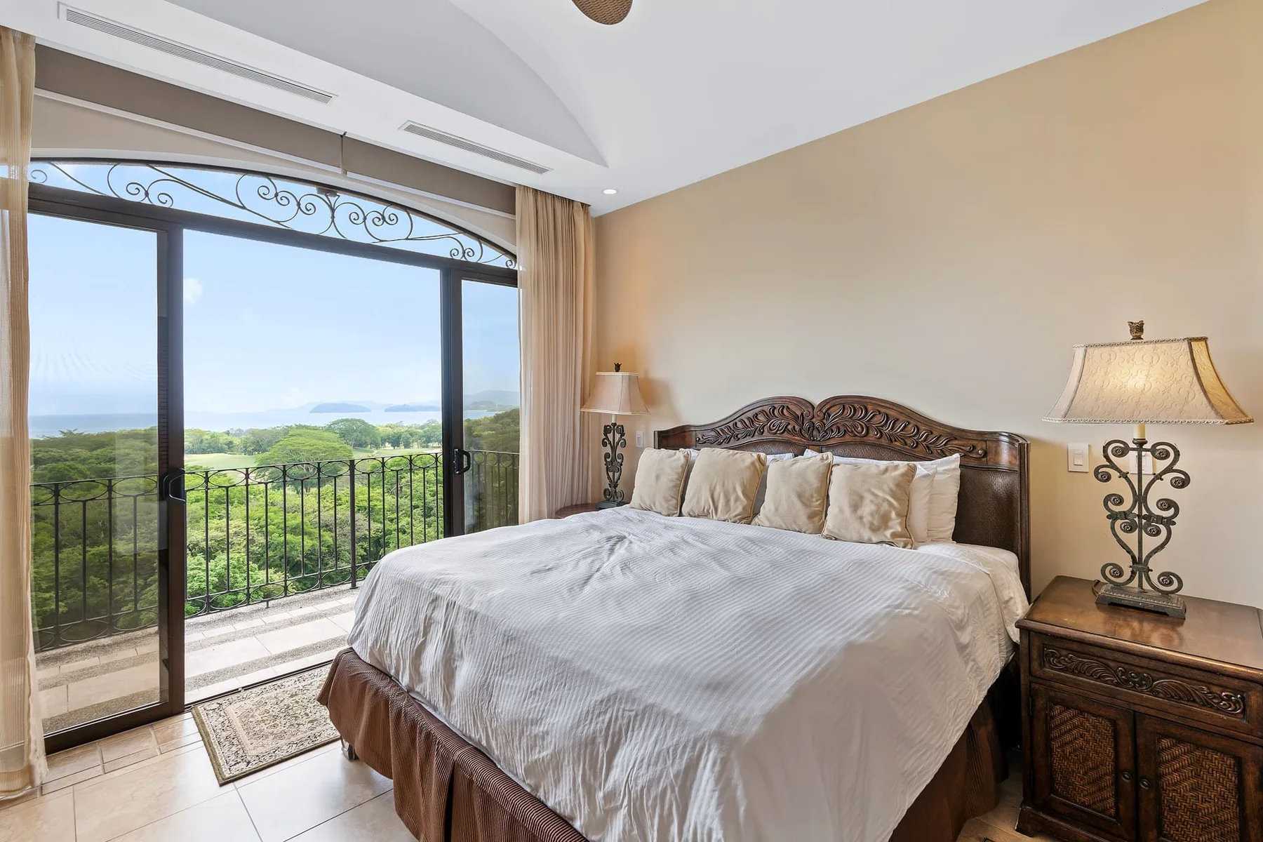 A bedroom with a large bed beside glass doors opening onto a balcony.