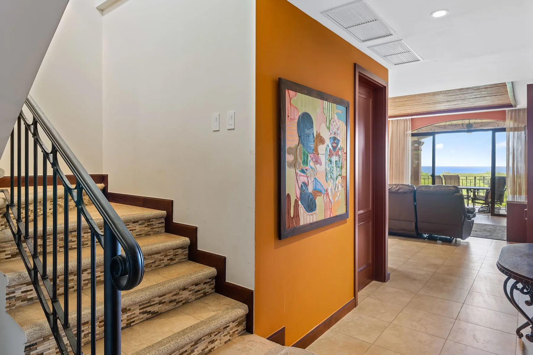 A tiled staircase and hallway lead toward a living area with a large window.