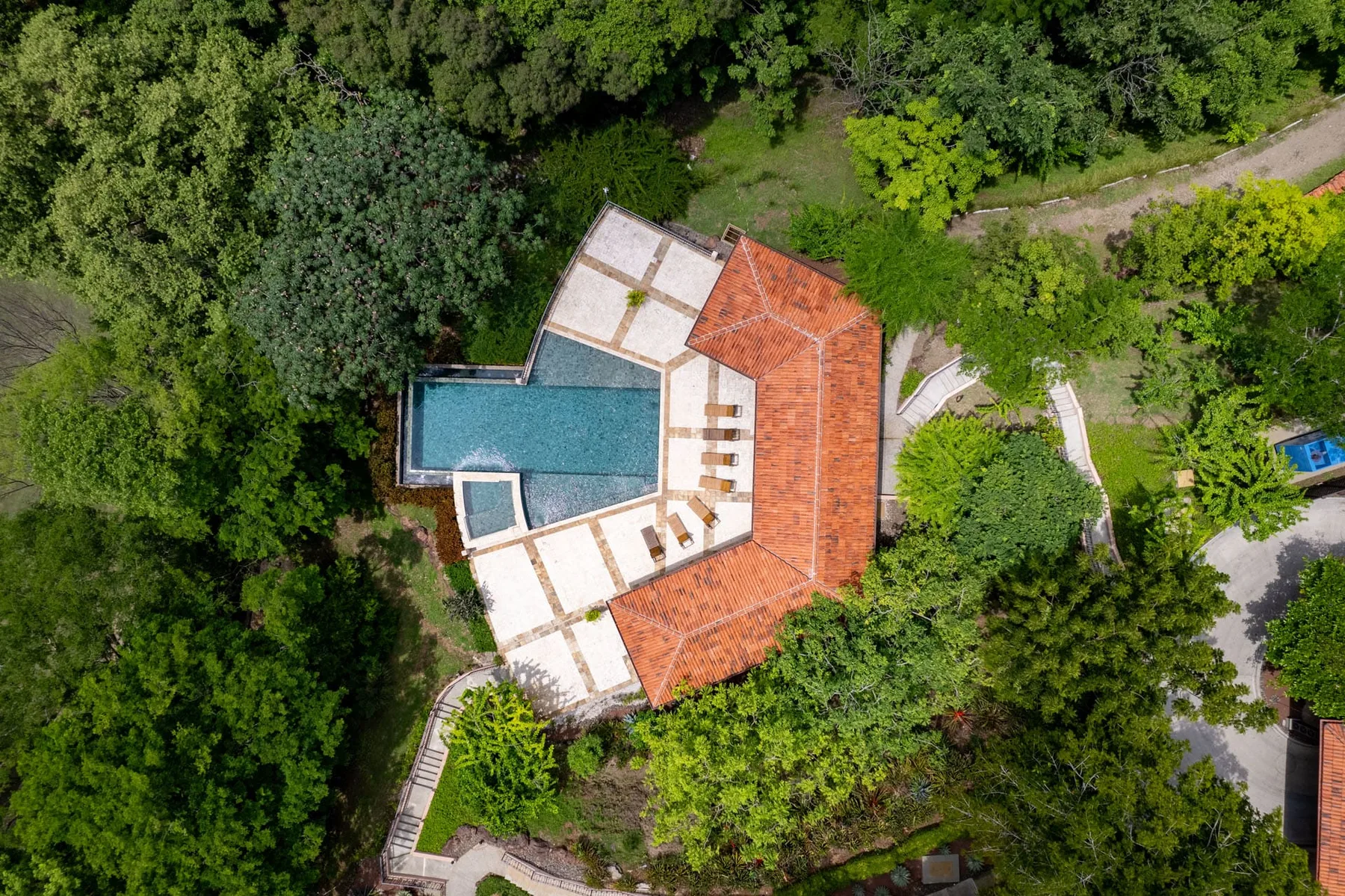 Shared amenity: Aerial view of a building with a swimming pool, surrounded by dense greenery.