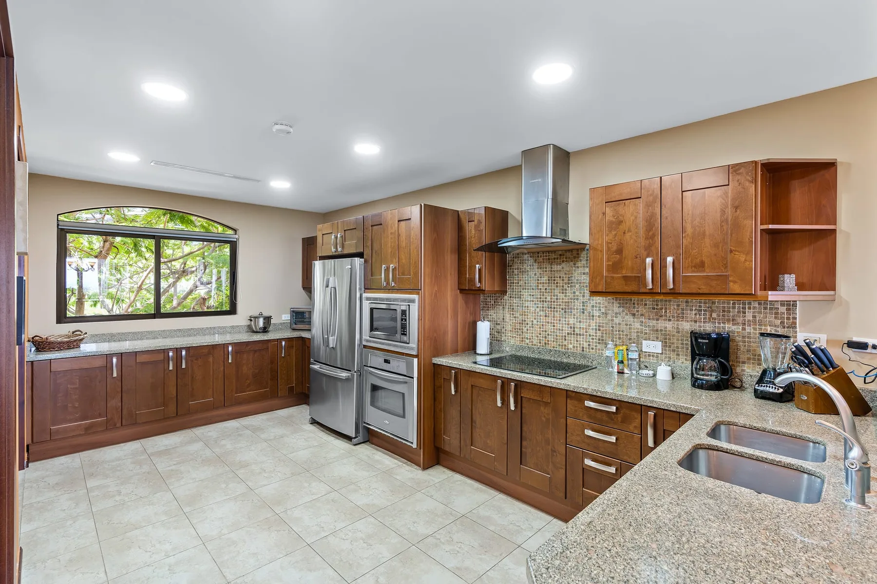 A spacious kitchen with wooden cabinets, stainless steel appliances, and a large window.