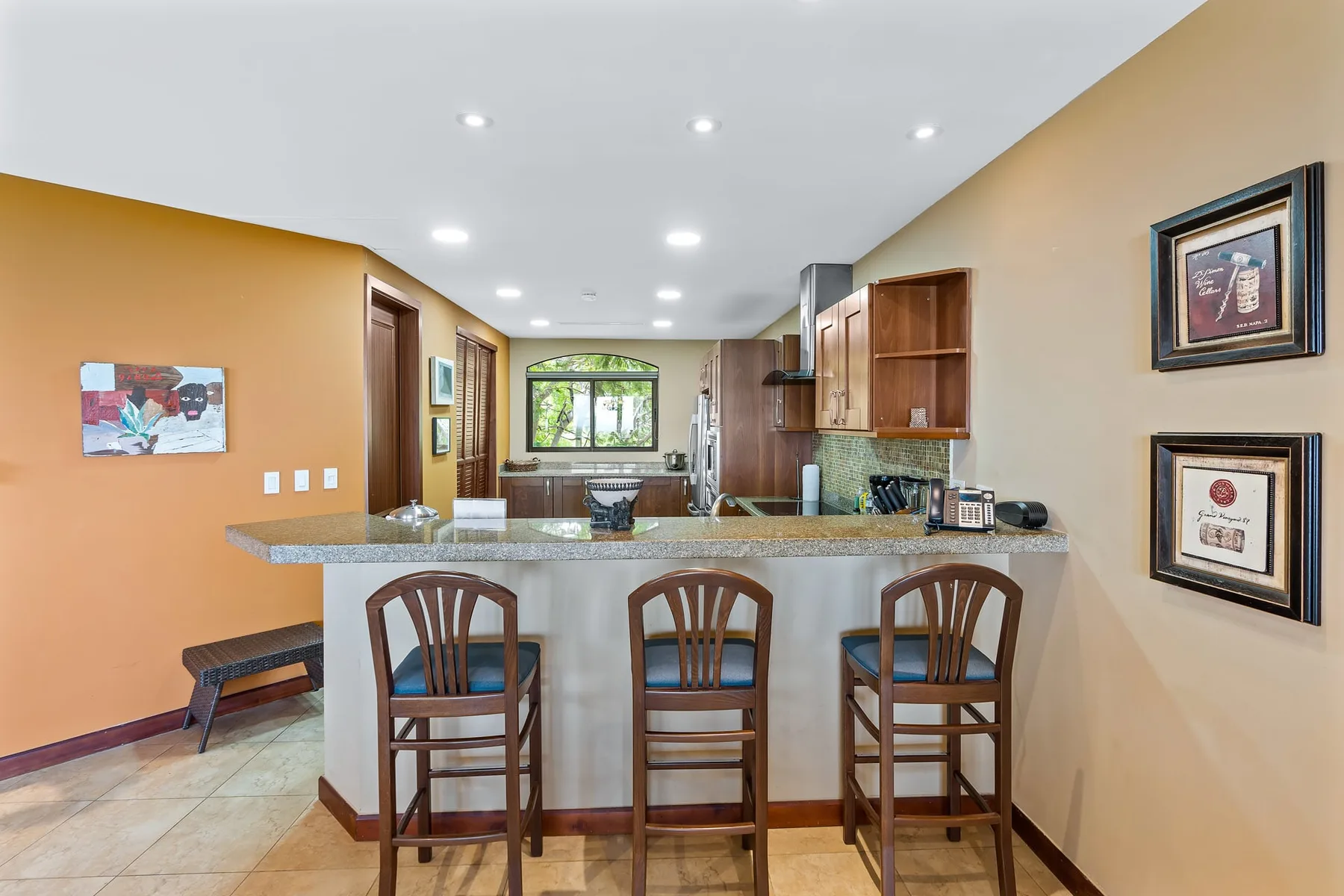A kitchen with a breakfast bar and seating overlooks a window at the far end.