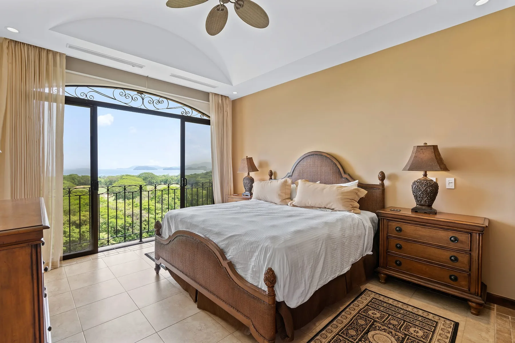 A bedroom with a large bed beside glass doors opening onto a balcony.