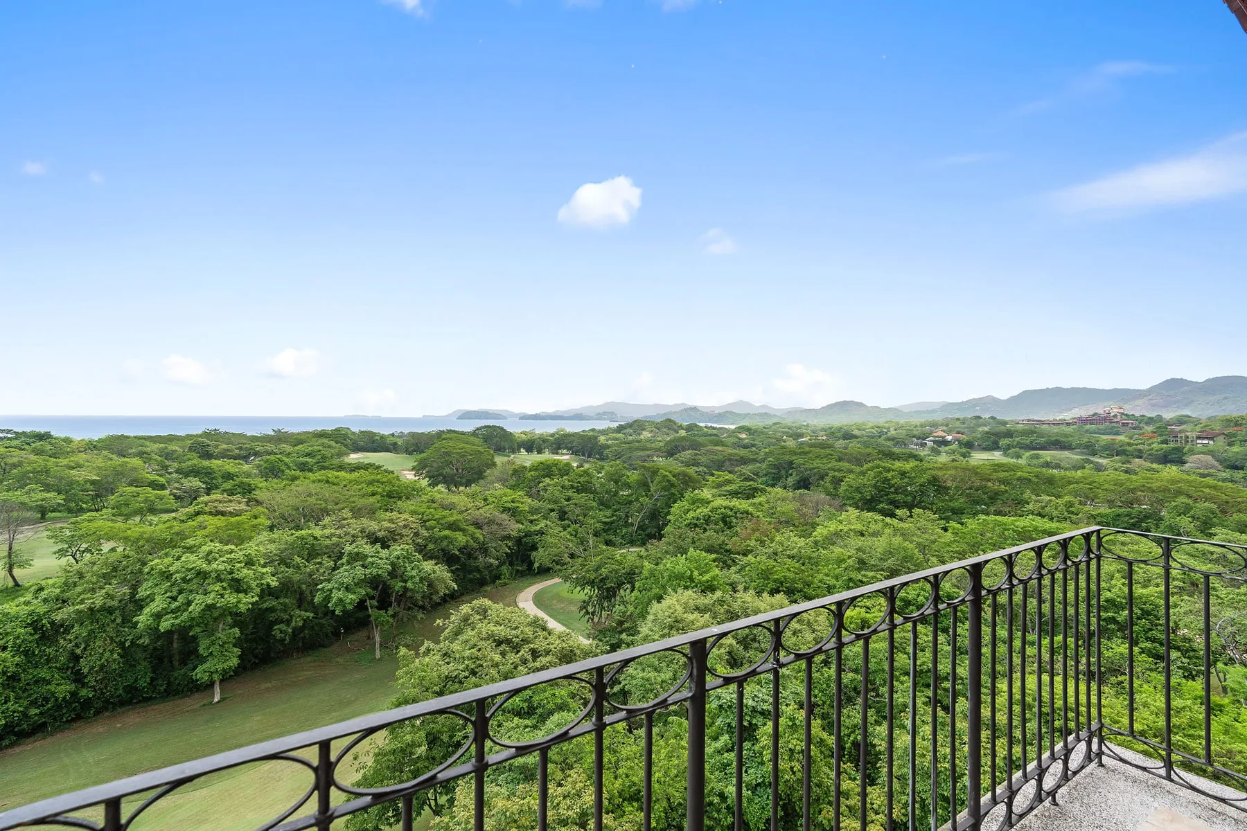 A balcony overlooks a broad expanse of green trees and distant hills.