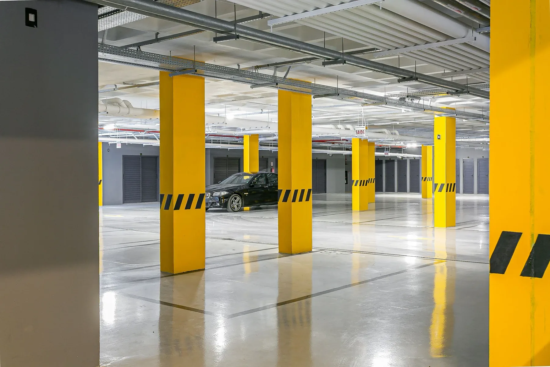 Shared amenity: A parking garage with yellow columns and a parked car.