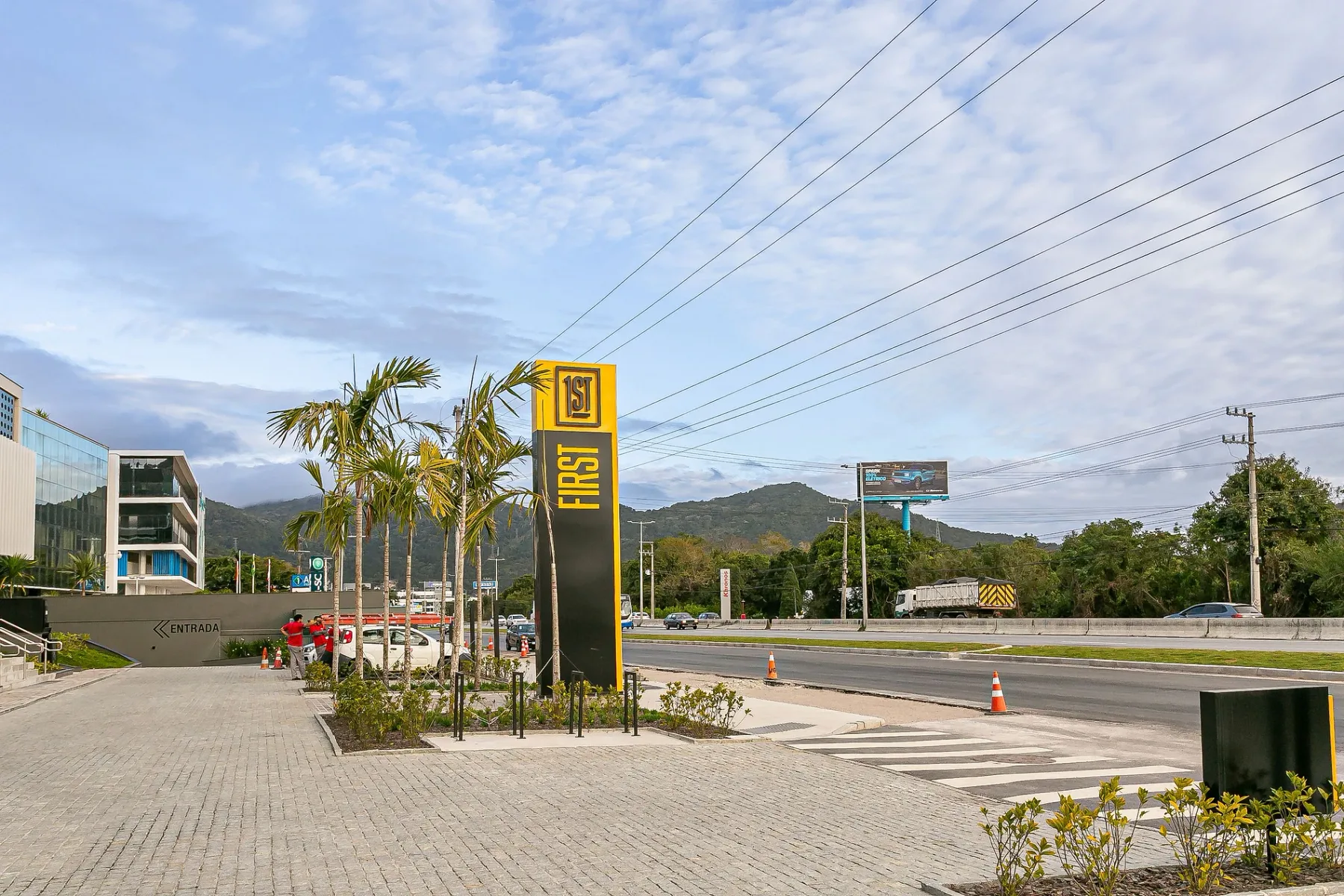 Shared amenity: Roadside entrance with palm trees beside a multi-lane road.