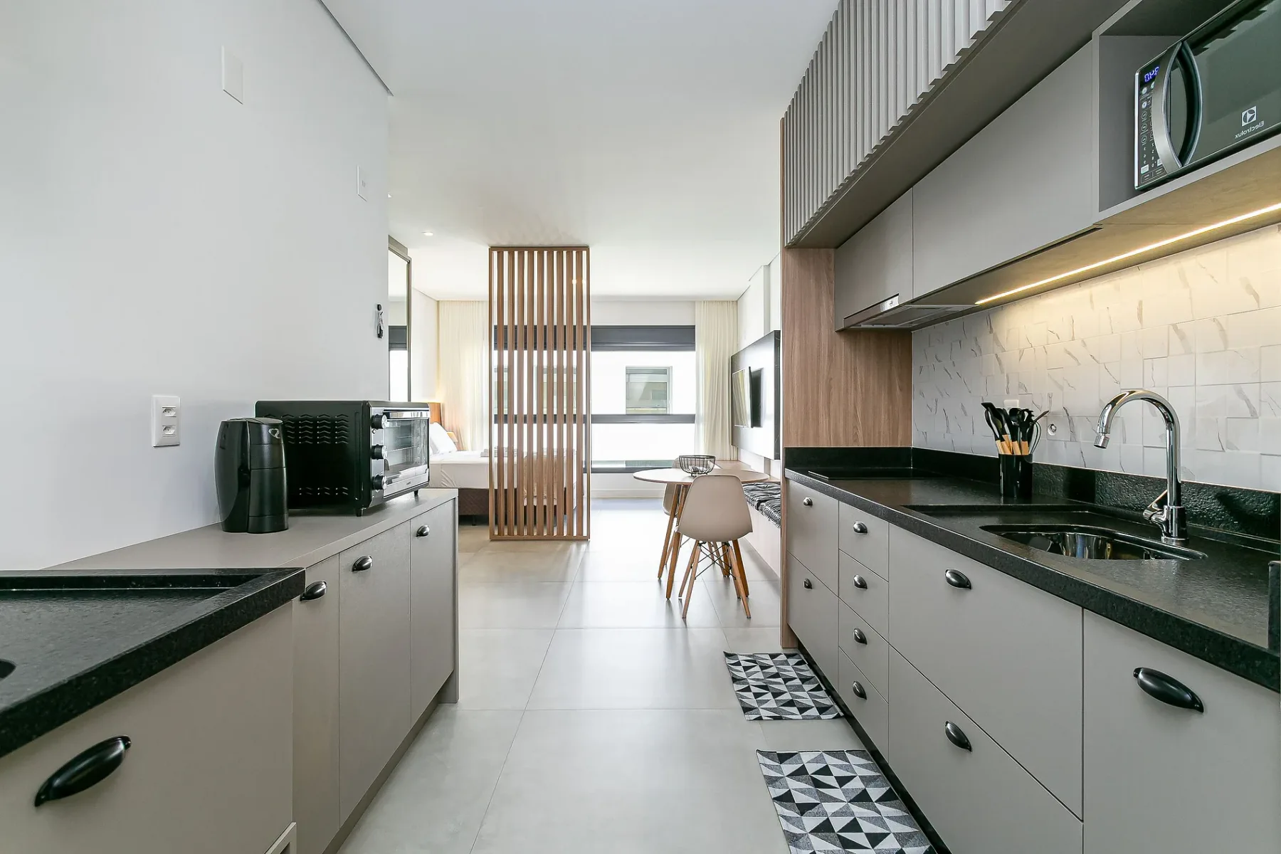 A modern kitchen with dark countertops and a dining area beyond.