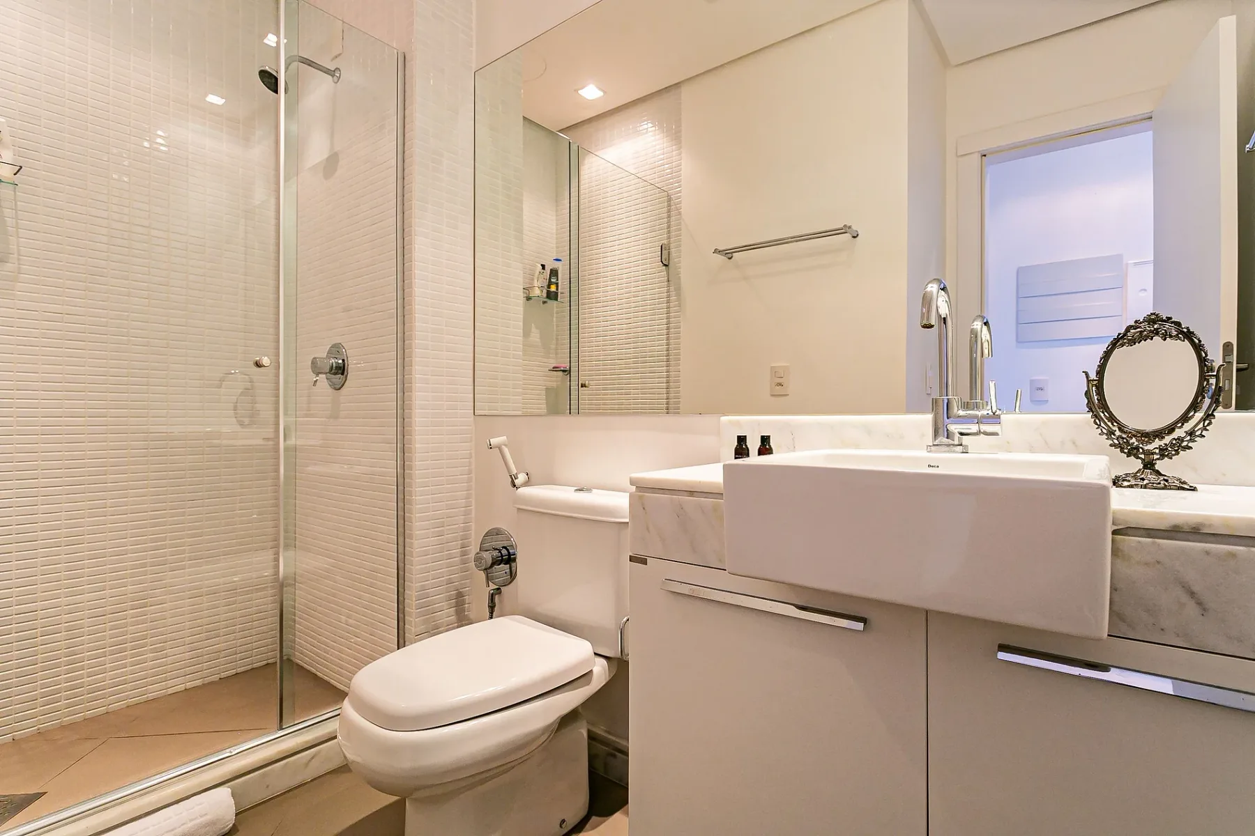 A bright bathroom with a glass shower, toilet, and vanity.