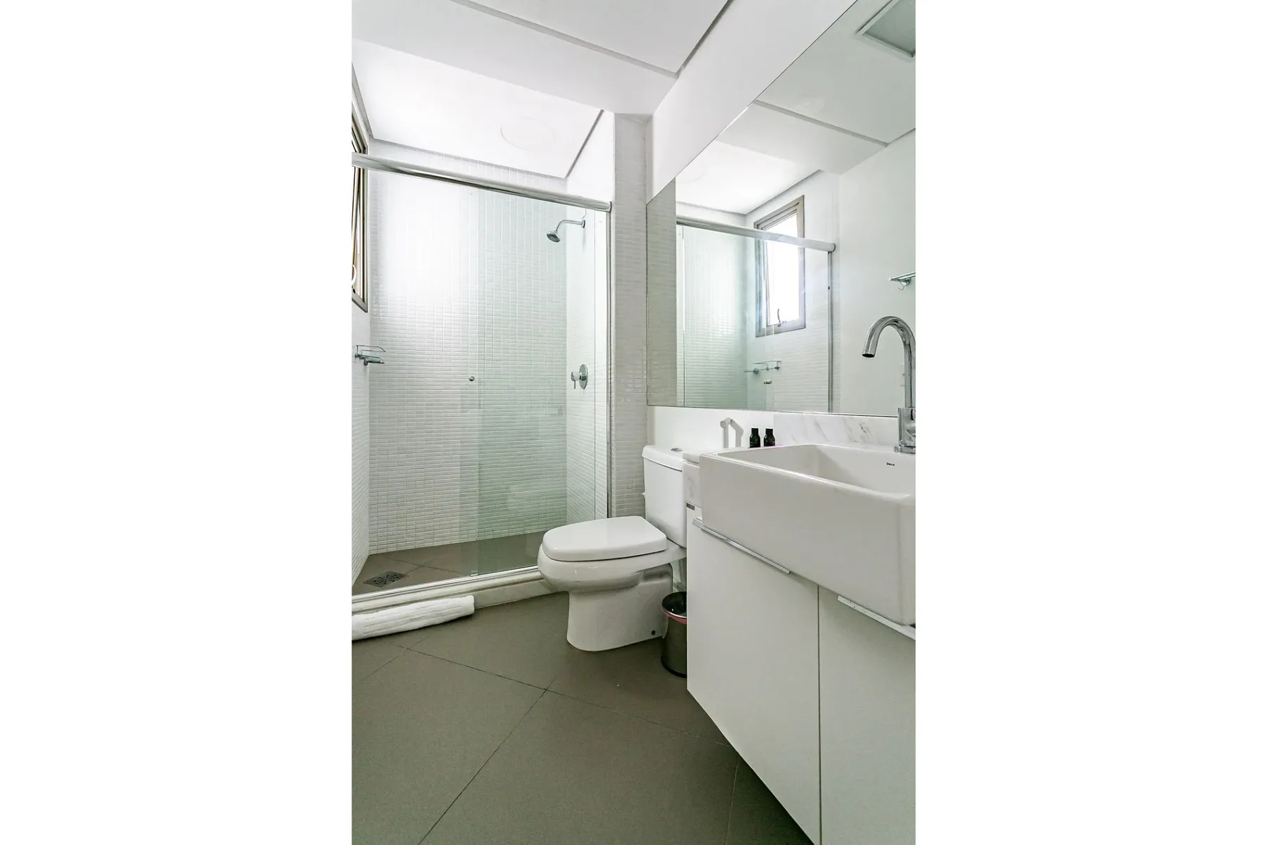 A bright bathroom with a glass shower and a white vanity.