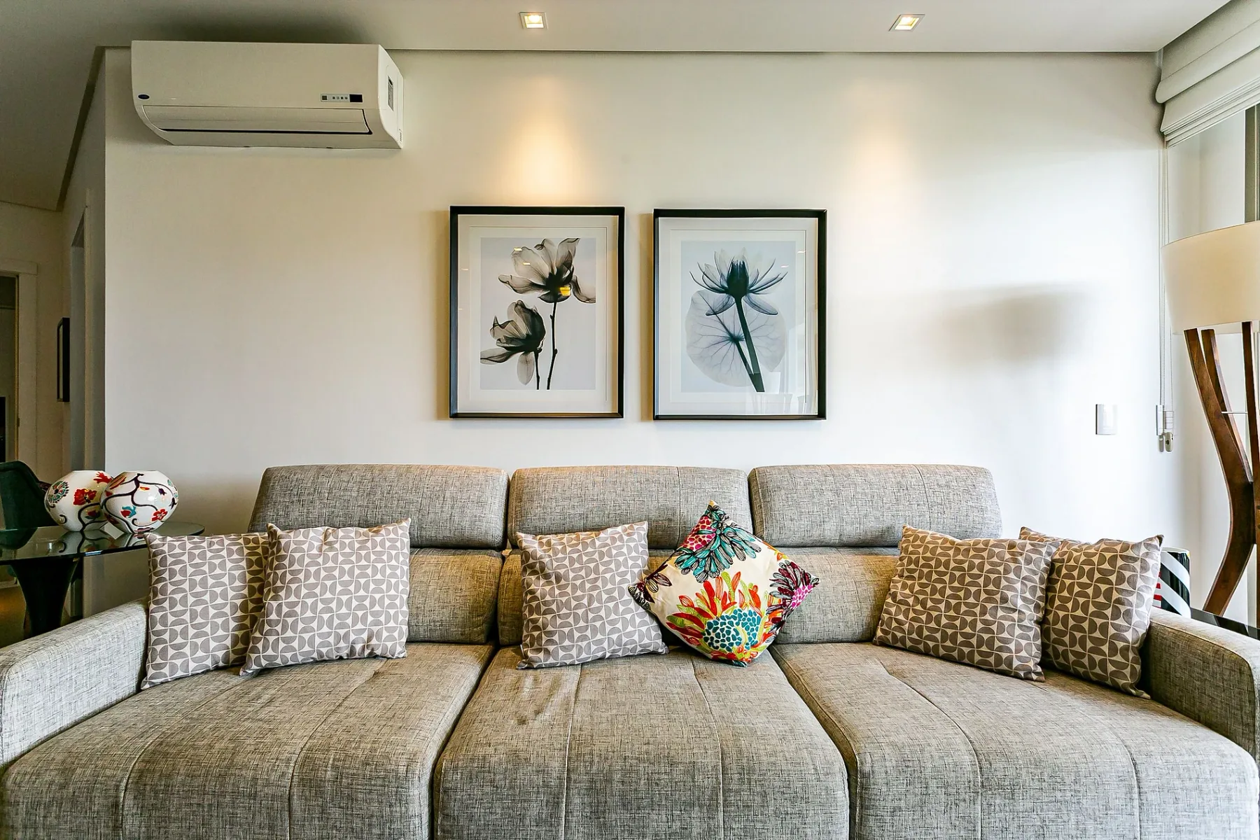 A bright living room with a sectional sofa and framed botanical prints.