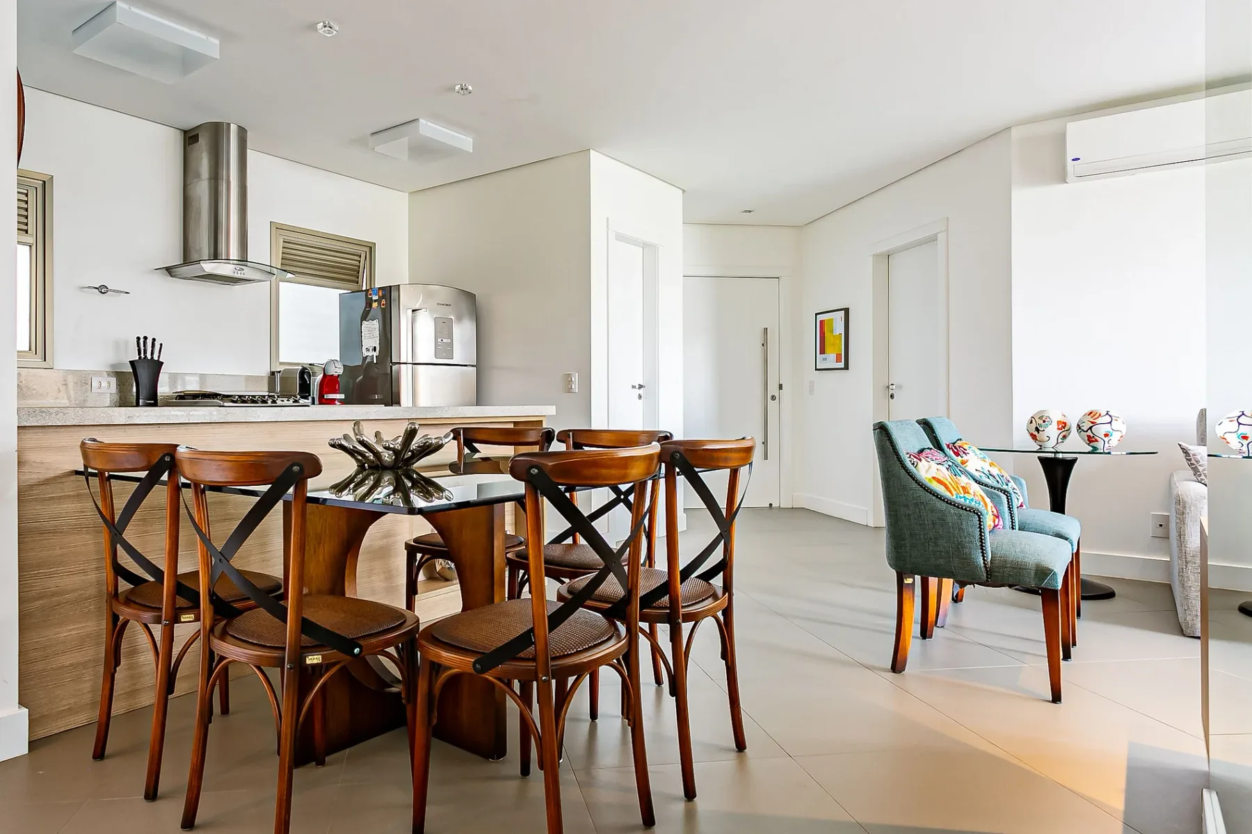 A bright dining area with a wooden table and chairs beside a kitchen.