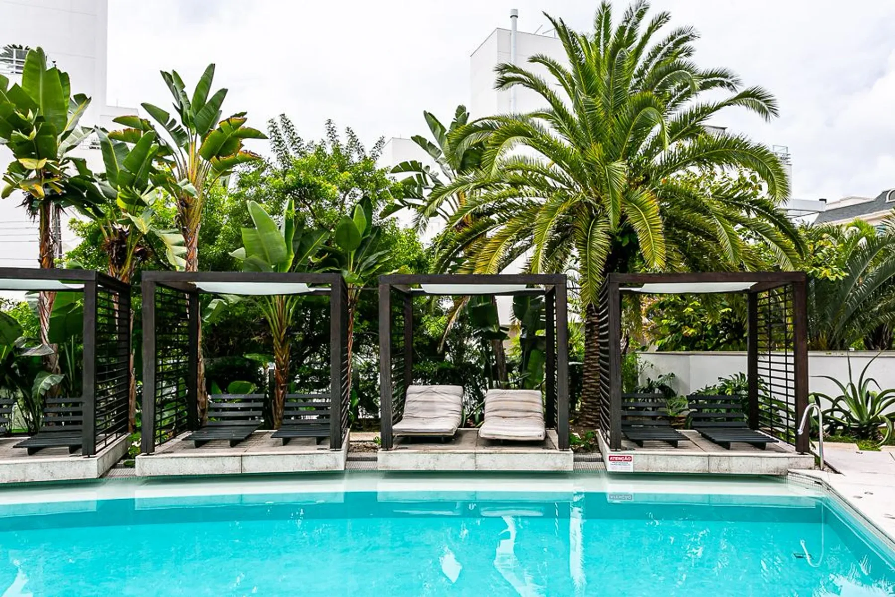 Shared amenity: An outdoor swimming pool is lined with shaded seating areas and tropical plants.