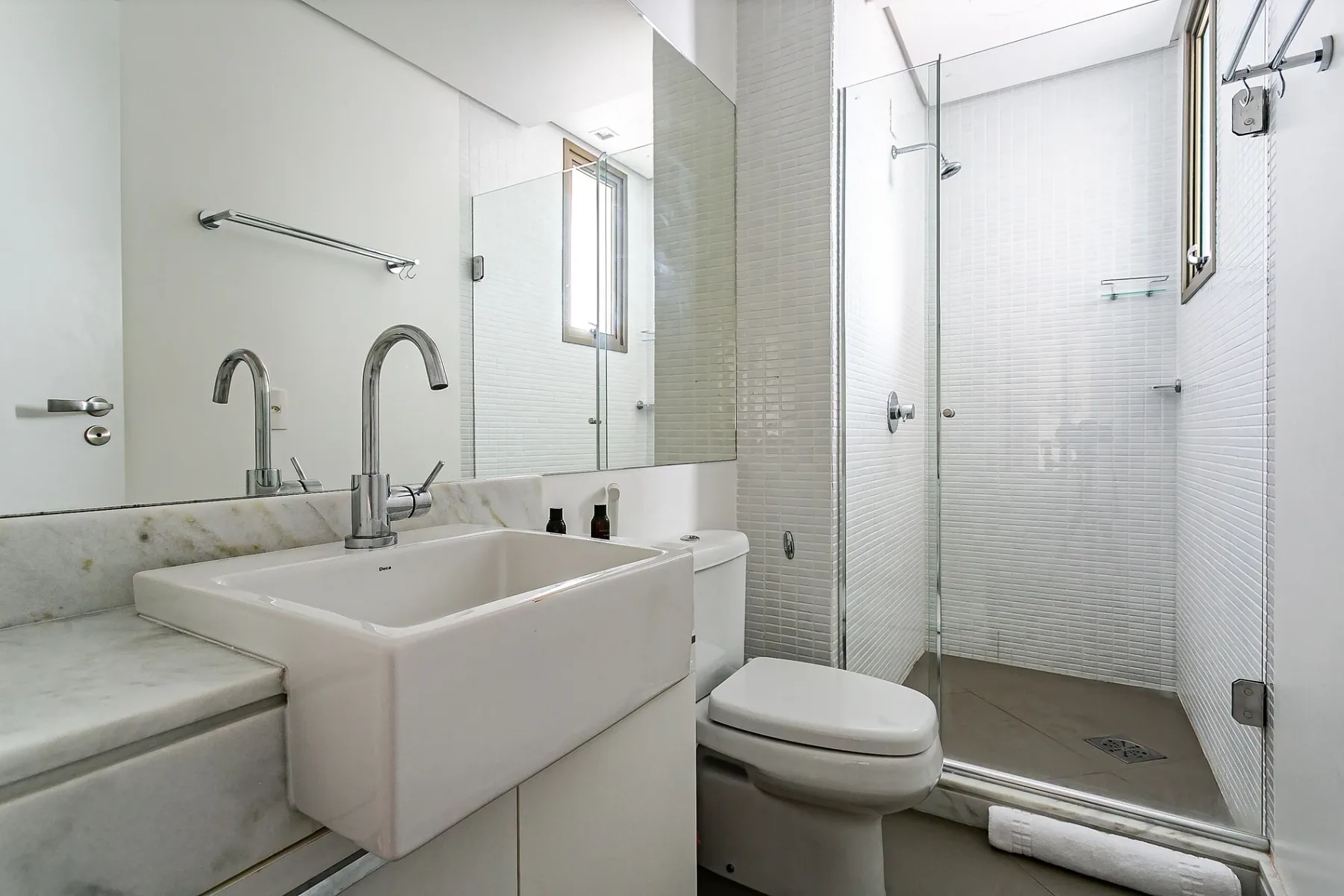 A bright bathroom with a sink, toilet, and glass shower.