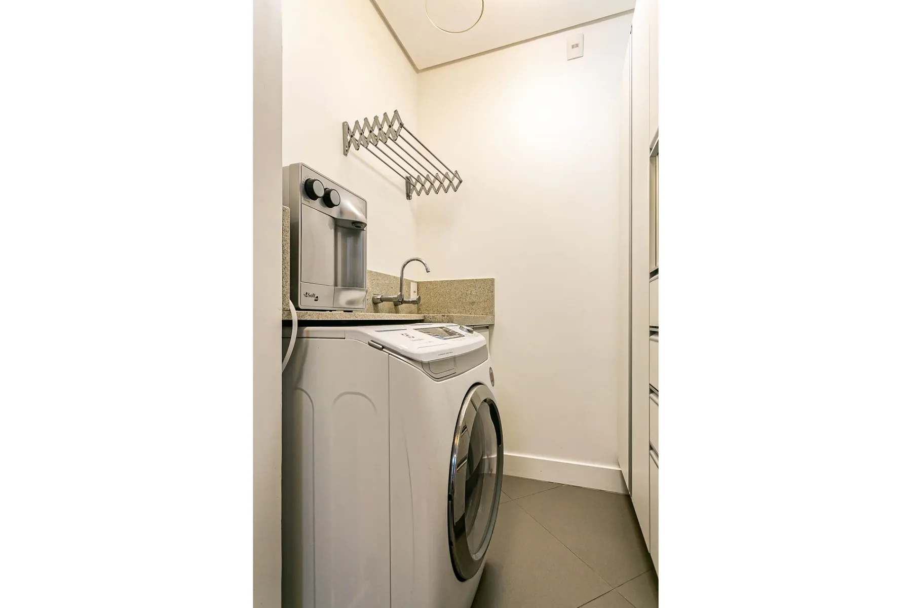 A compact laundry area with a washing machine and wall-mounted drying rack.