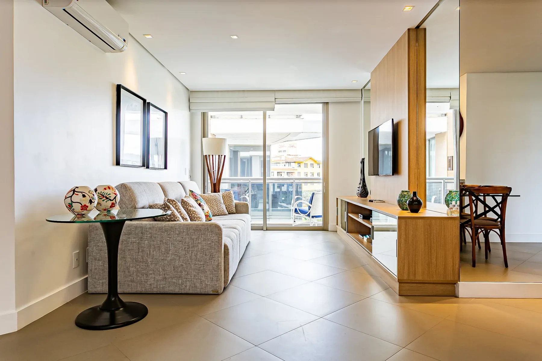 A bright living room with seating, a television, and large windows.