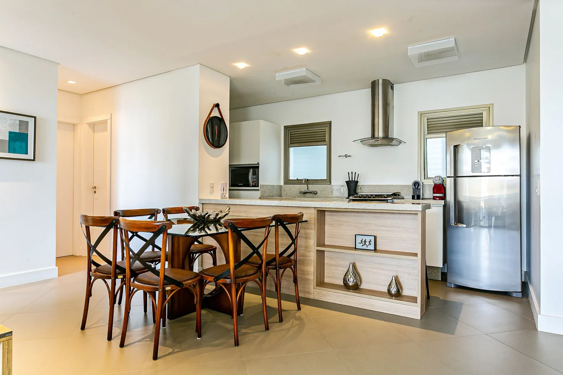A bright kitchen and dining area with a table, chairs, and stainless-steel appliances.