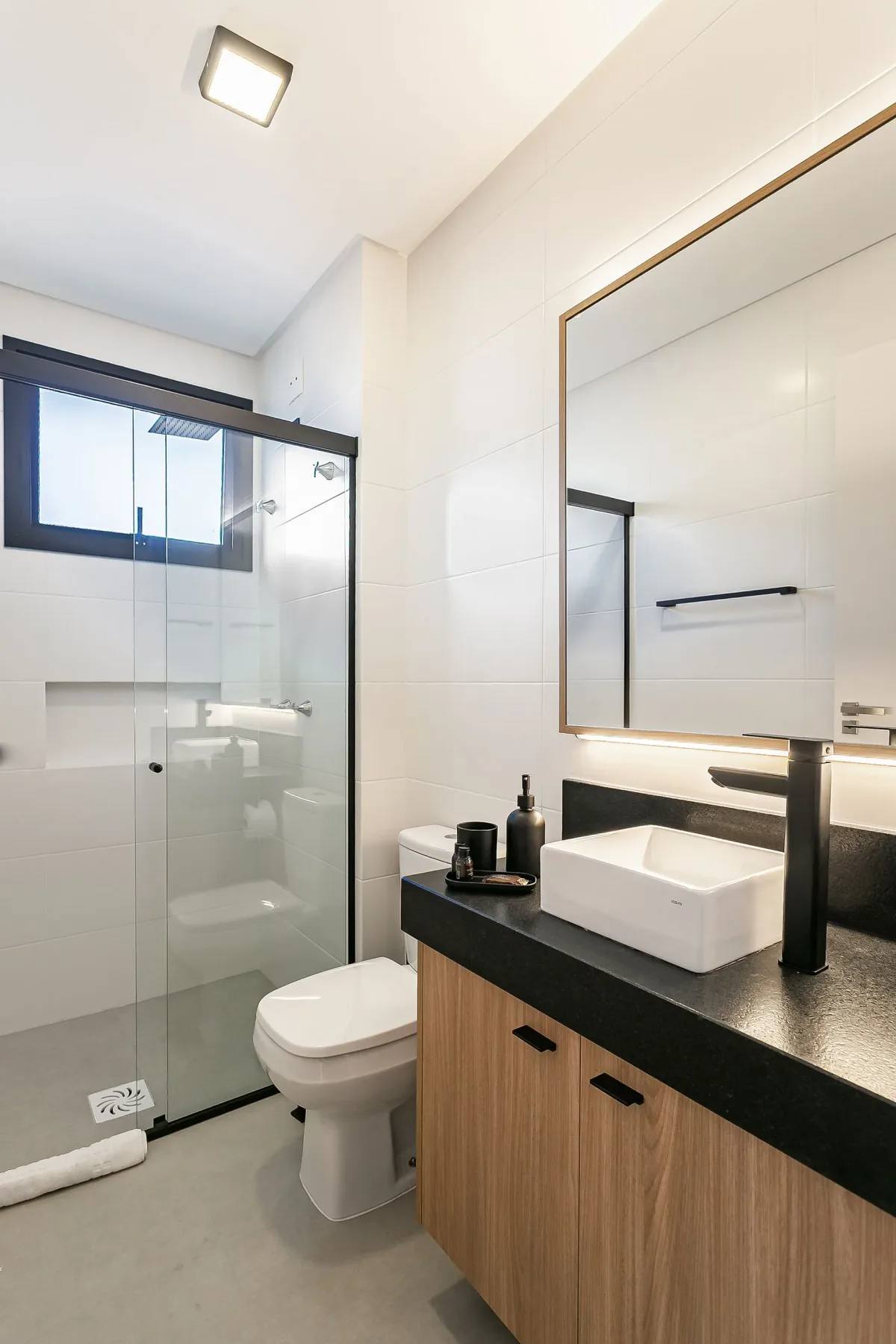 A bright bathroom with a glass shower, toilet, and vanity.