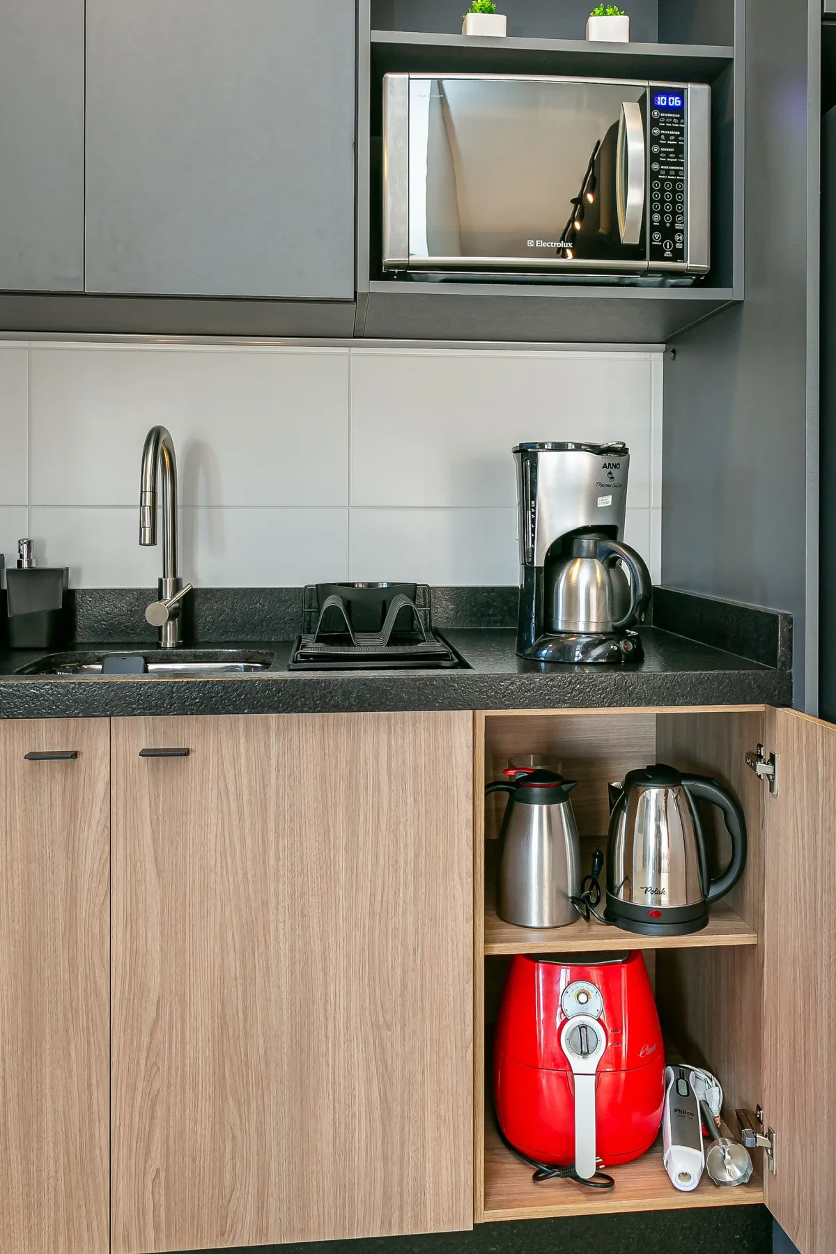 A compact kitchen counter with a sink, coffee maker, and microwave.