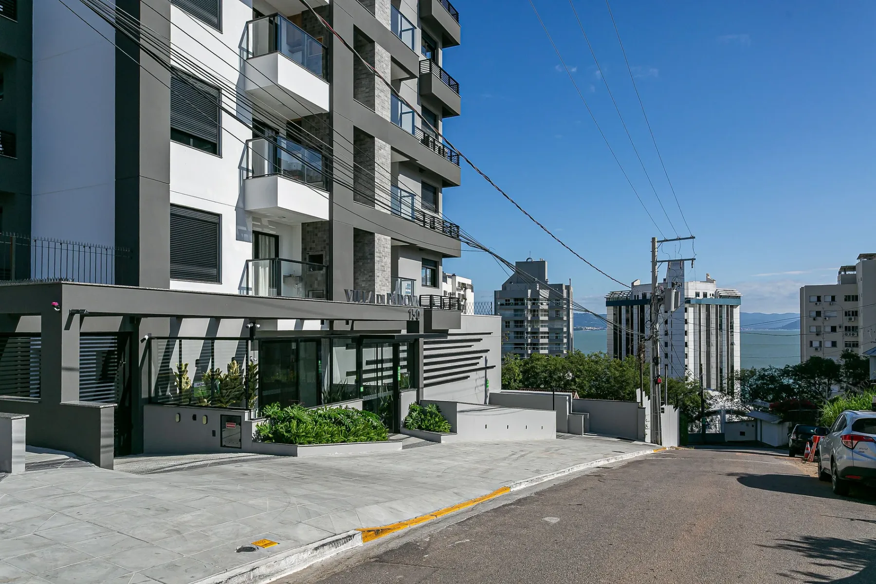 Shared amenity: A modern apartment building faces a paved street with planted greenery.