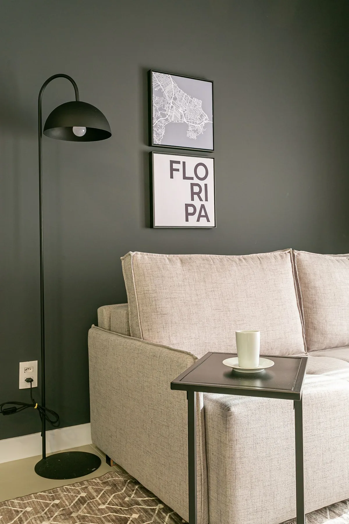A living room with a light-colored sofa, floor lamp, and side table.