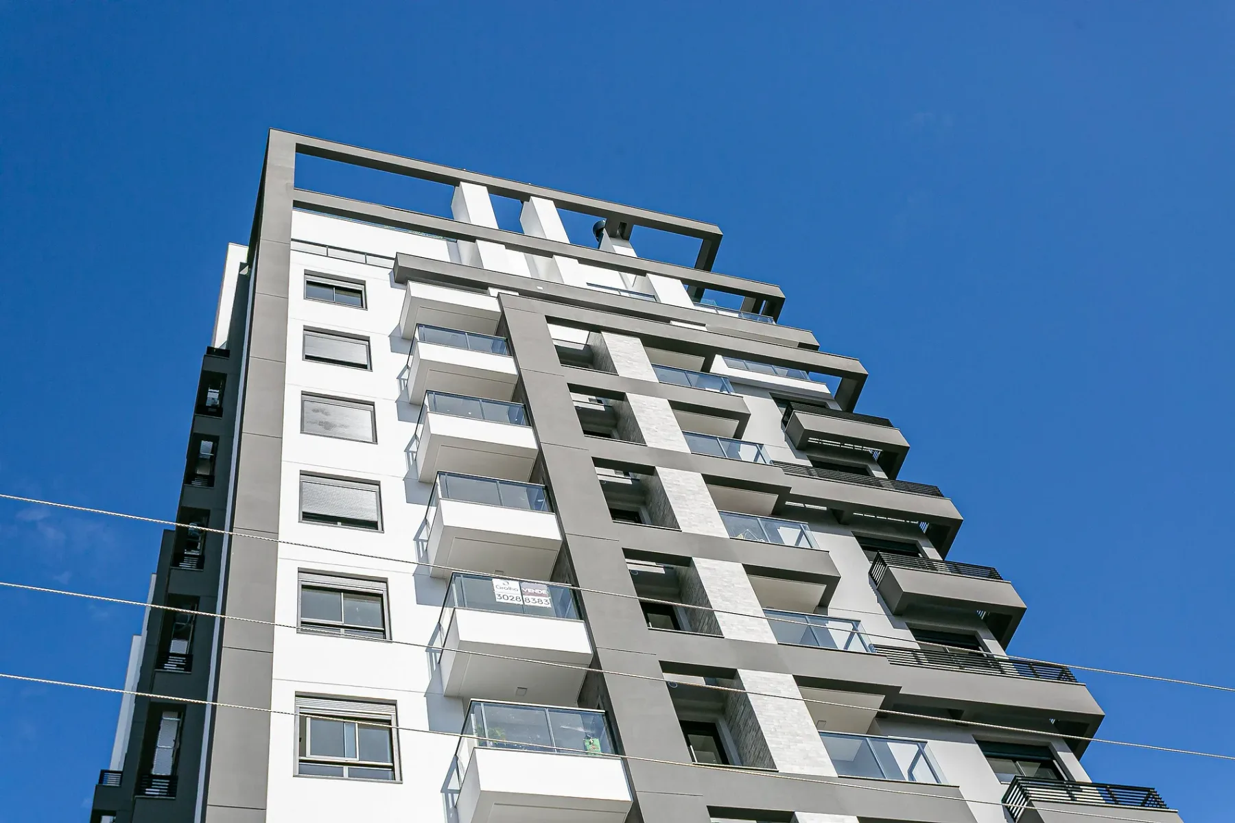 Shared amenity: Modern multi-story building with rows of balconies against a clear blue sky.