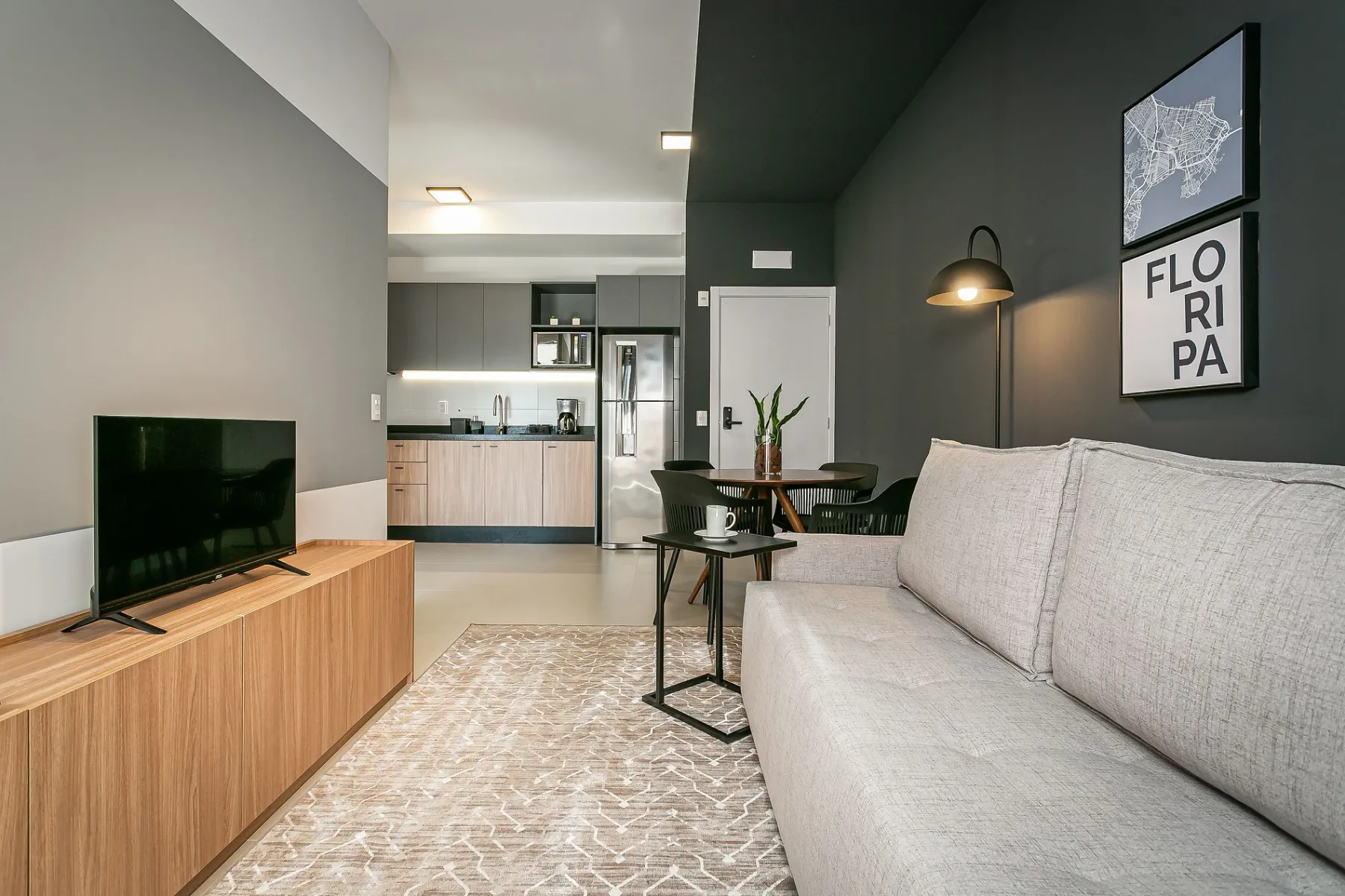 A modern living room with a sofa, television, and open kitchen.