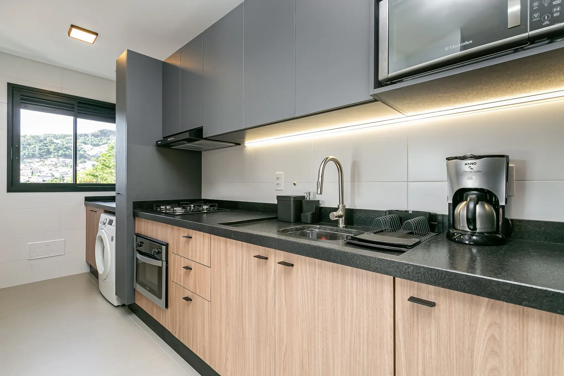 A modern kitchen with a long countertop, sink, and built-in appliances.