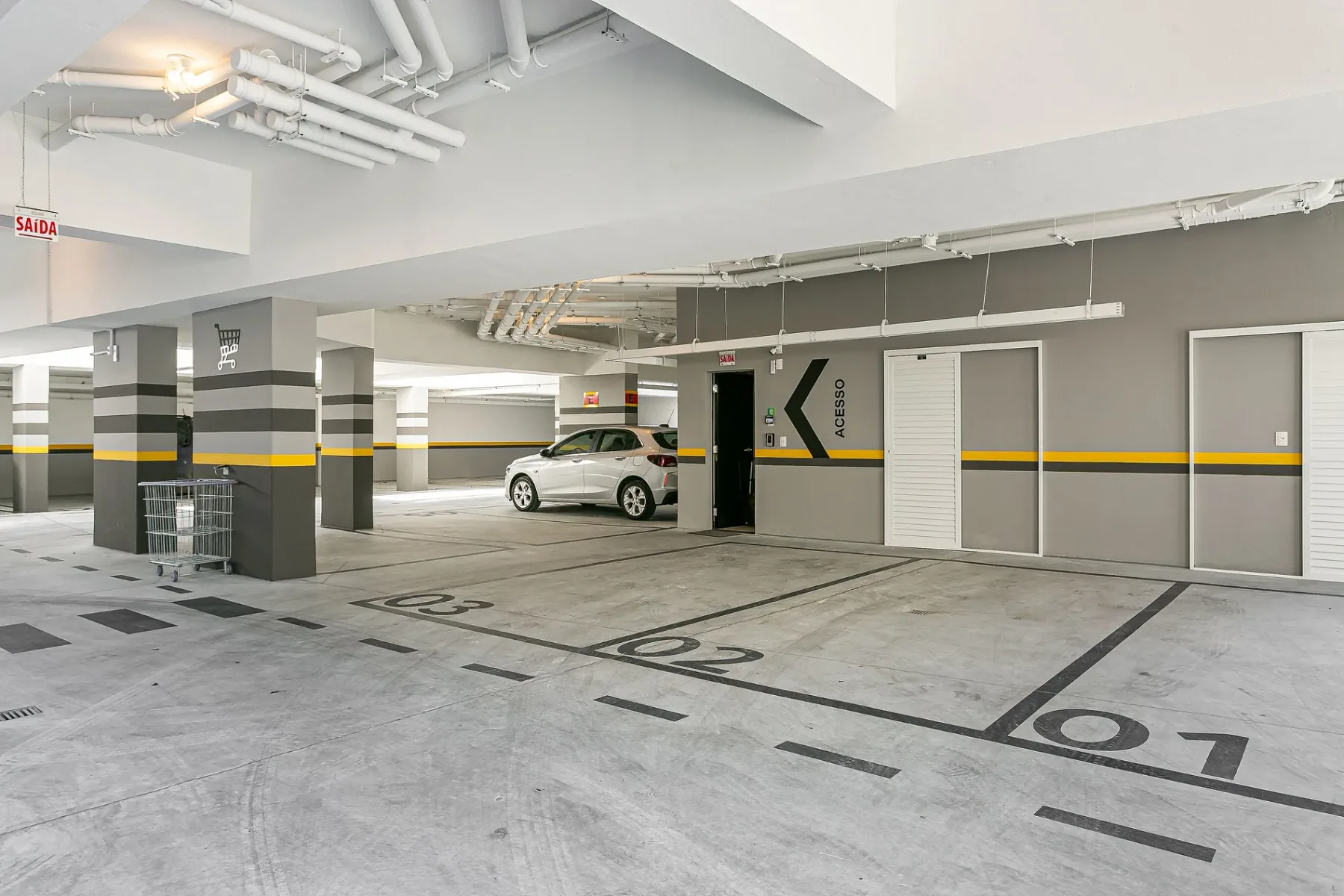 Shared amenity: Underground parking garage with painted parking spaces and a parked car.