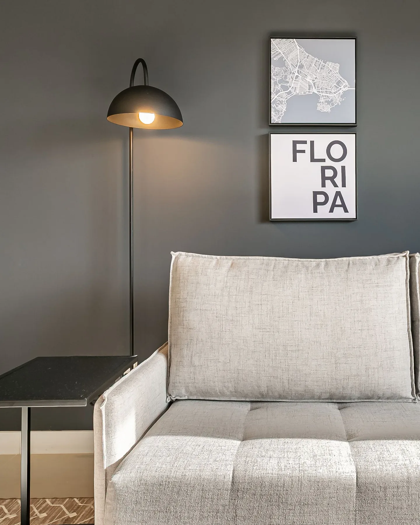 A living room seating area with a floor lamp and framed wall art.