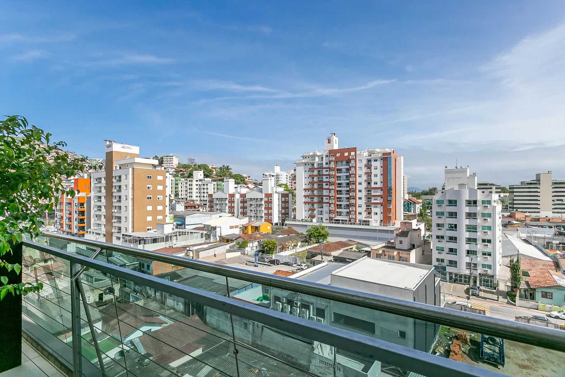 City buildings and rooftops are visible beyond a glass balcony railing.