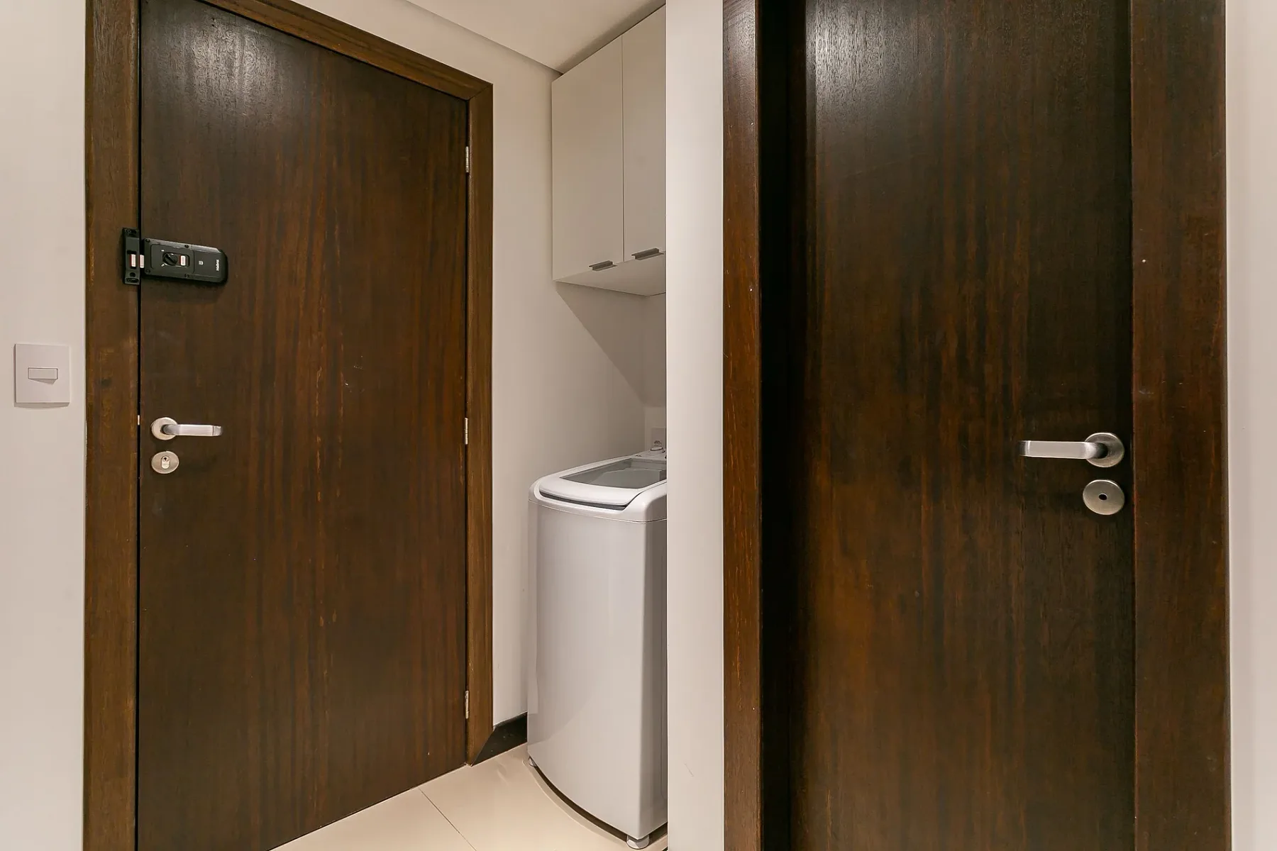 An interior hallway with two dark wooden doors and a washing machine.