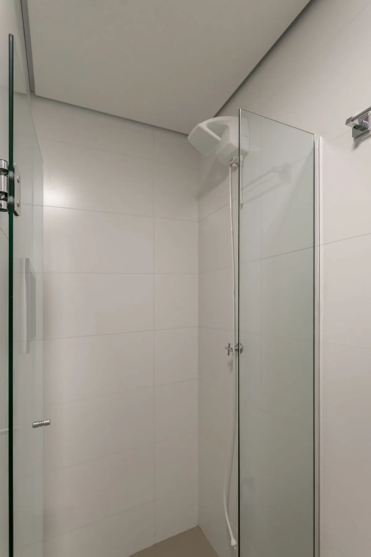 A tiled bathroom with a glass shower and handheld showerhead.