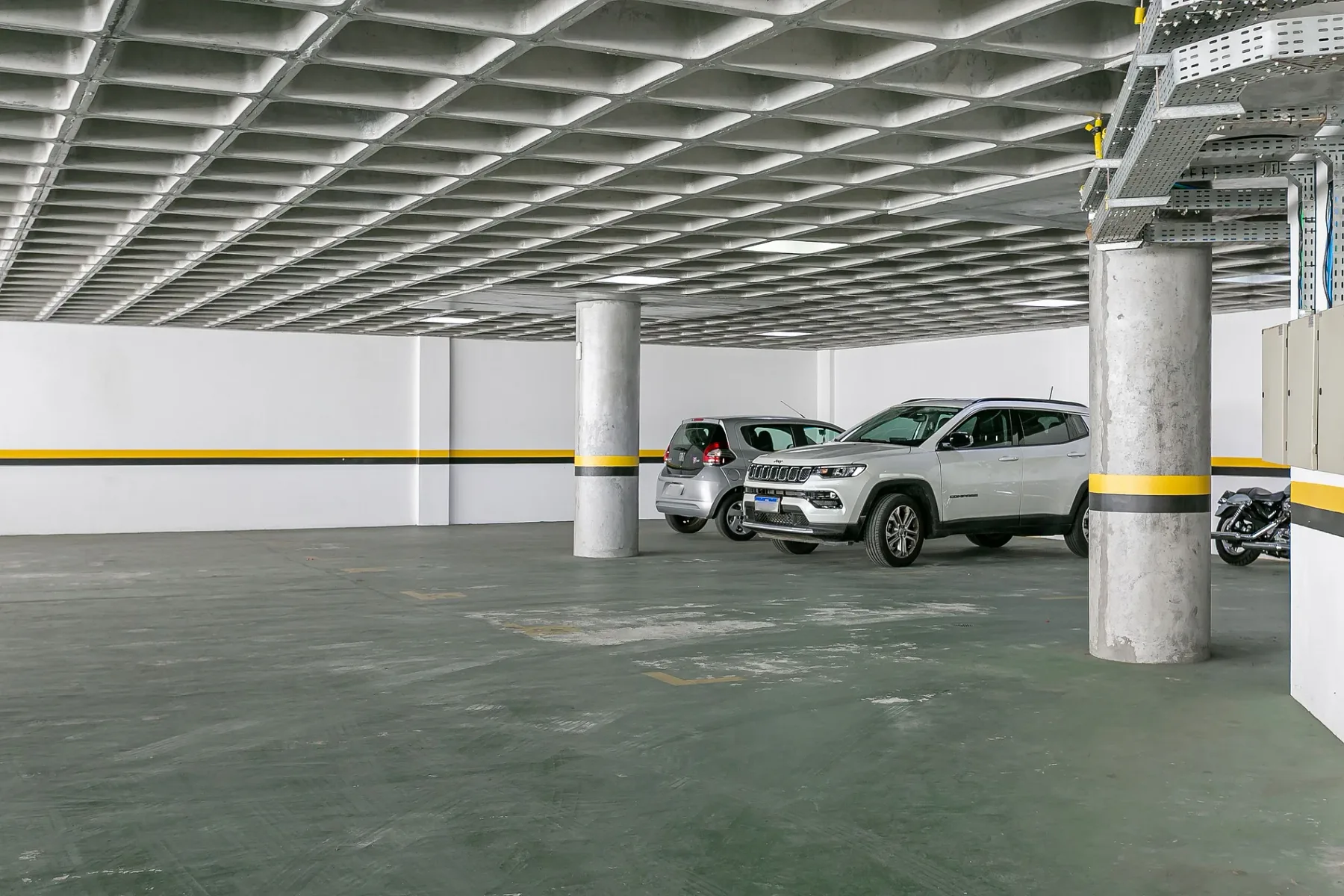 Shared amenity: An indoor parking garage with parked vehicles and concrete support columns.