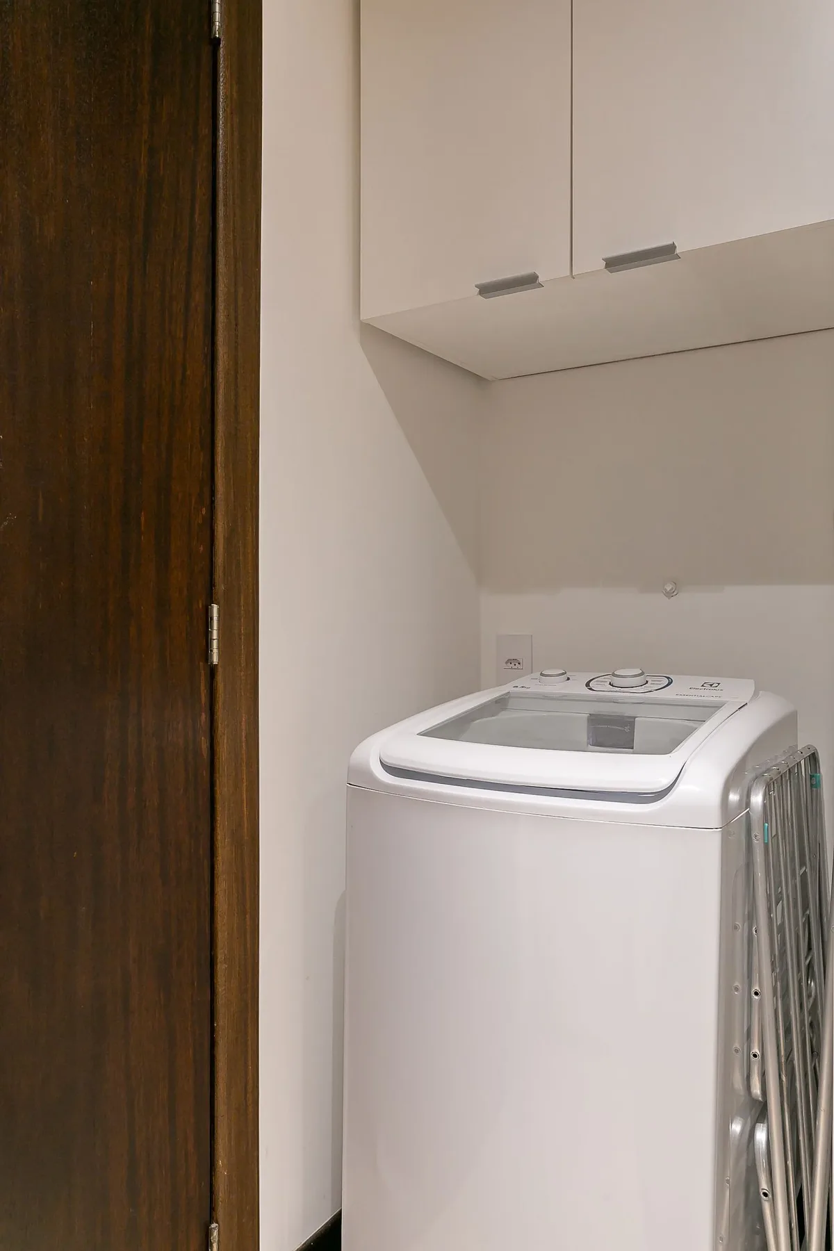 A laundry area with a top-loading washing machine beneath wall cabinets.